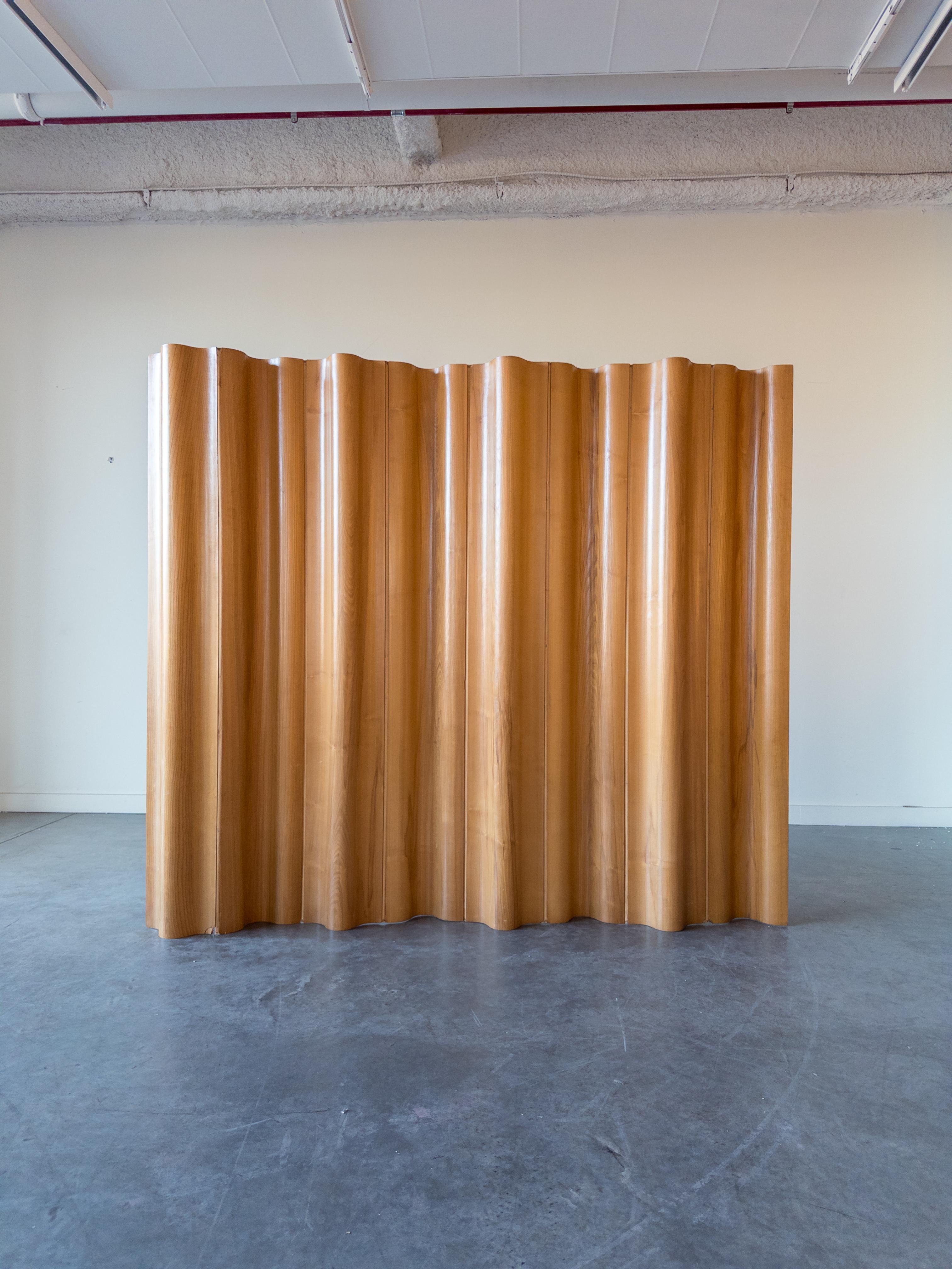 An early molded plywood screen divider in calico ash, designed by Charles & Ray Eames, manufactured by Herman Miller. The screen's ingenious design allows it to be formed into a variety of appealing shapes. Cotton canvas hinges are flexible,
