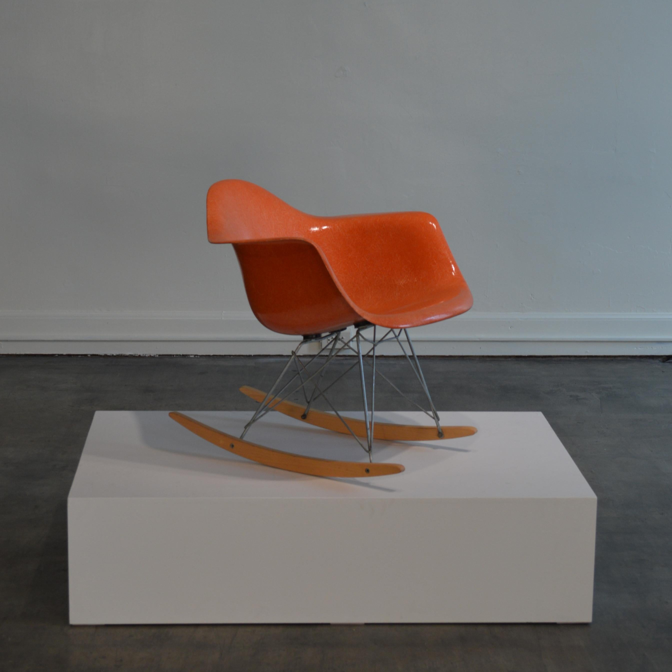 Ray and Charles Eames designed RAR rocking chair in red orange. Made, circa 1950s by Herman Miller of Zeeland, Michigan, US. Pristine example of the this icon of modern design. Molded fiberglass seat is in nearly unused condition, with almost no UV