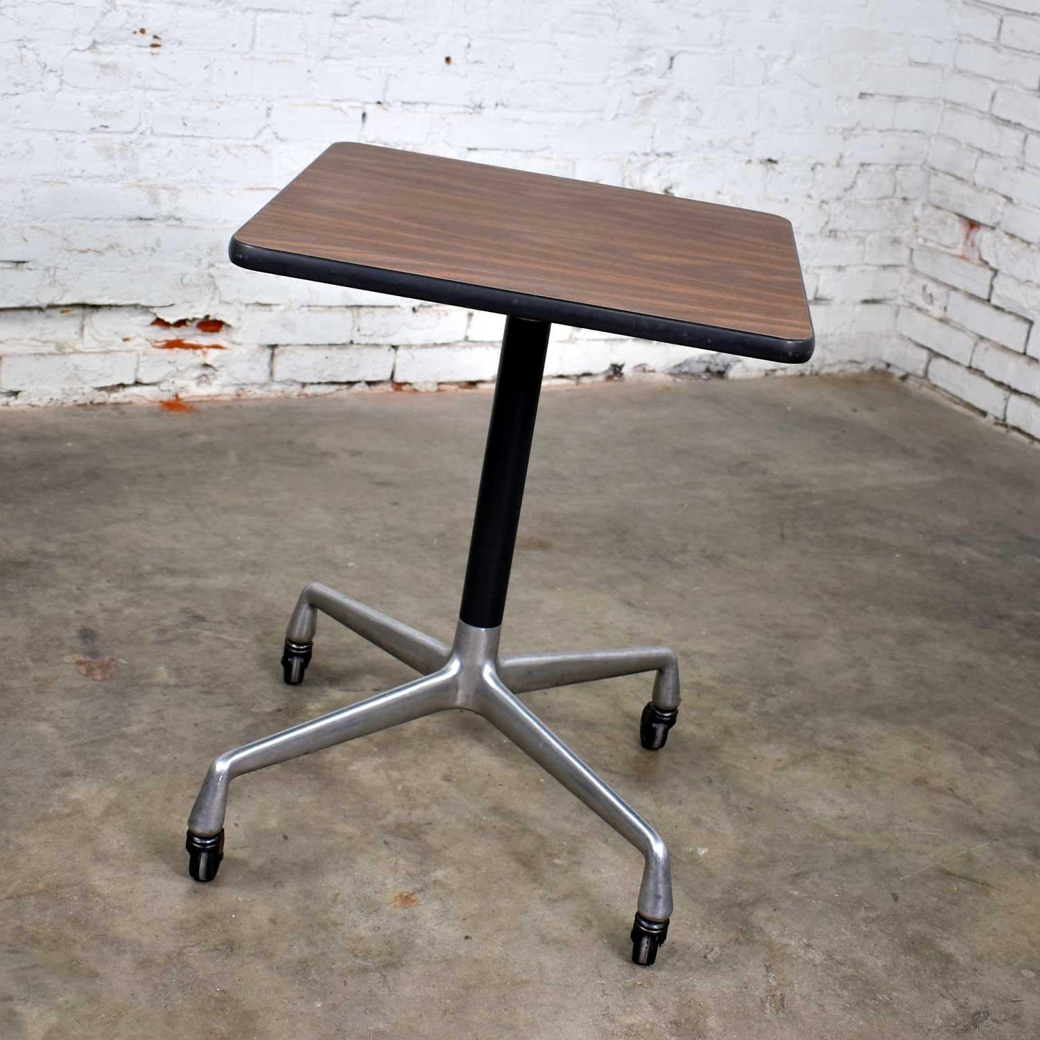 Handsome square rolling side table designed by Charles and Ray Eames for Herman Miller. Comprised of a faux wood grain laminate top and universal base. In wonderful vintage condition with the normal signs of age. There is some darkening to the