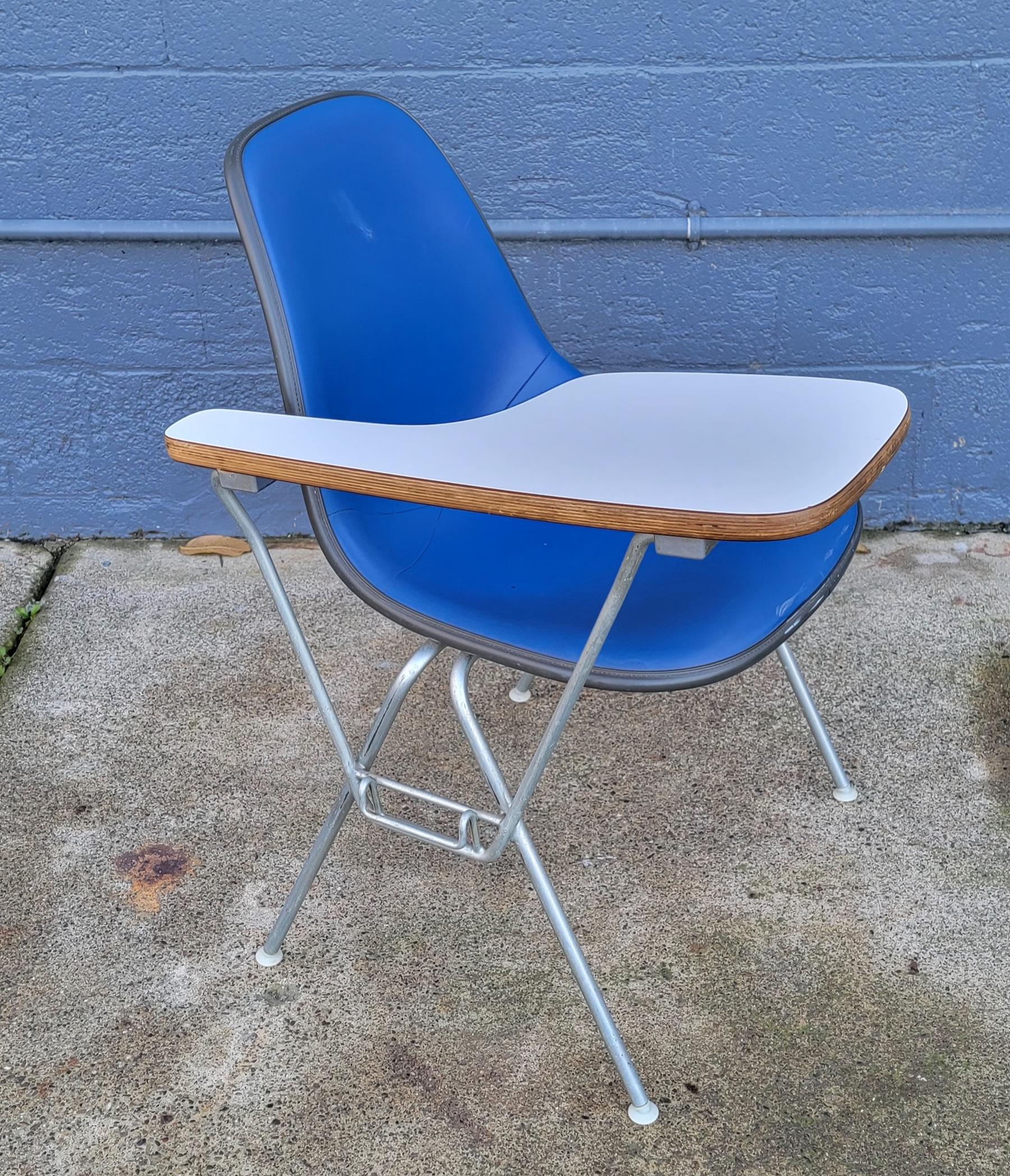 Eames for Herman Miller formed fiberglass desk chair. Desk top flips up for easier seating. Retains Herman Miller labels. Vibrant blue upholstery. Original condition. Scuff mark center of seat back.