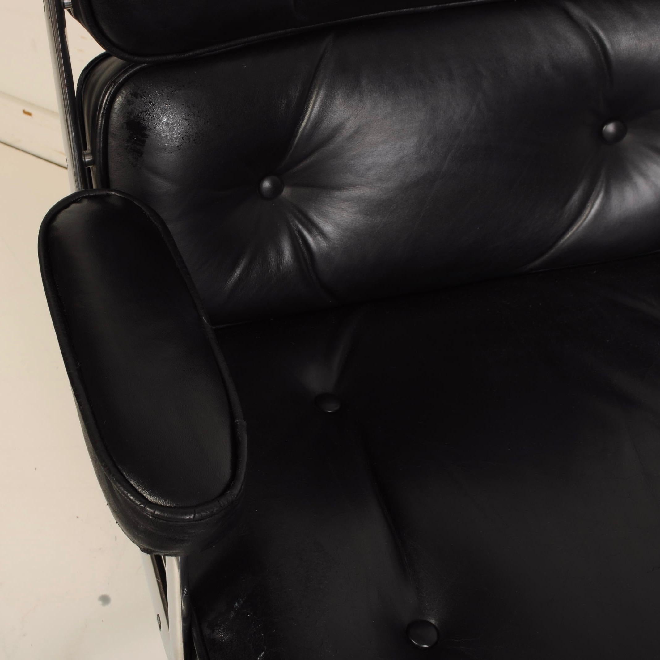 An executive office chair designed by Charles and Ray Eames, manufactured by Herman Miller, with tufted back, seat and armrest in black leather against aluminum frame, on segmented swivel base with caster wheels. Markings include manufacturer's