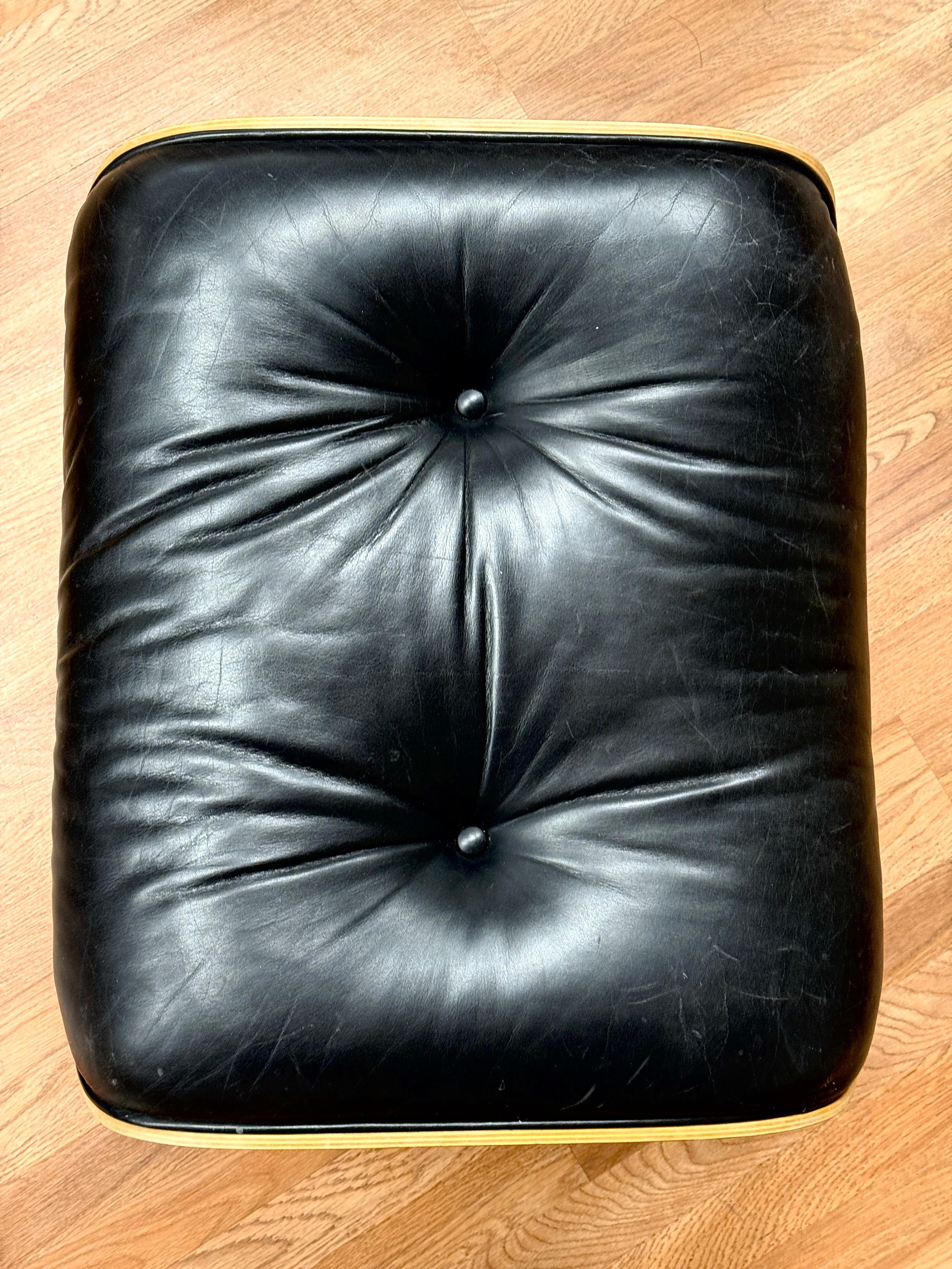 A nice vintage Eames 671 Ottoman with a cherry veneer and black leather. The label looks like it dates to 1970-1984, although I’m not certain.  The leather is in good condition although there are some marks to the leather. The wood is good with