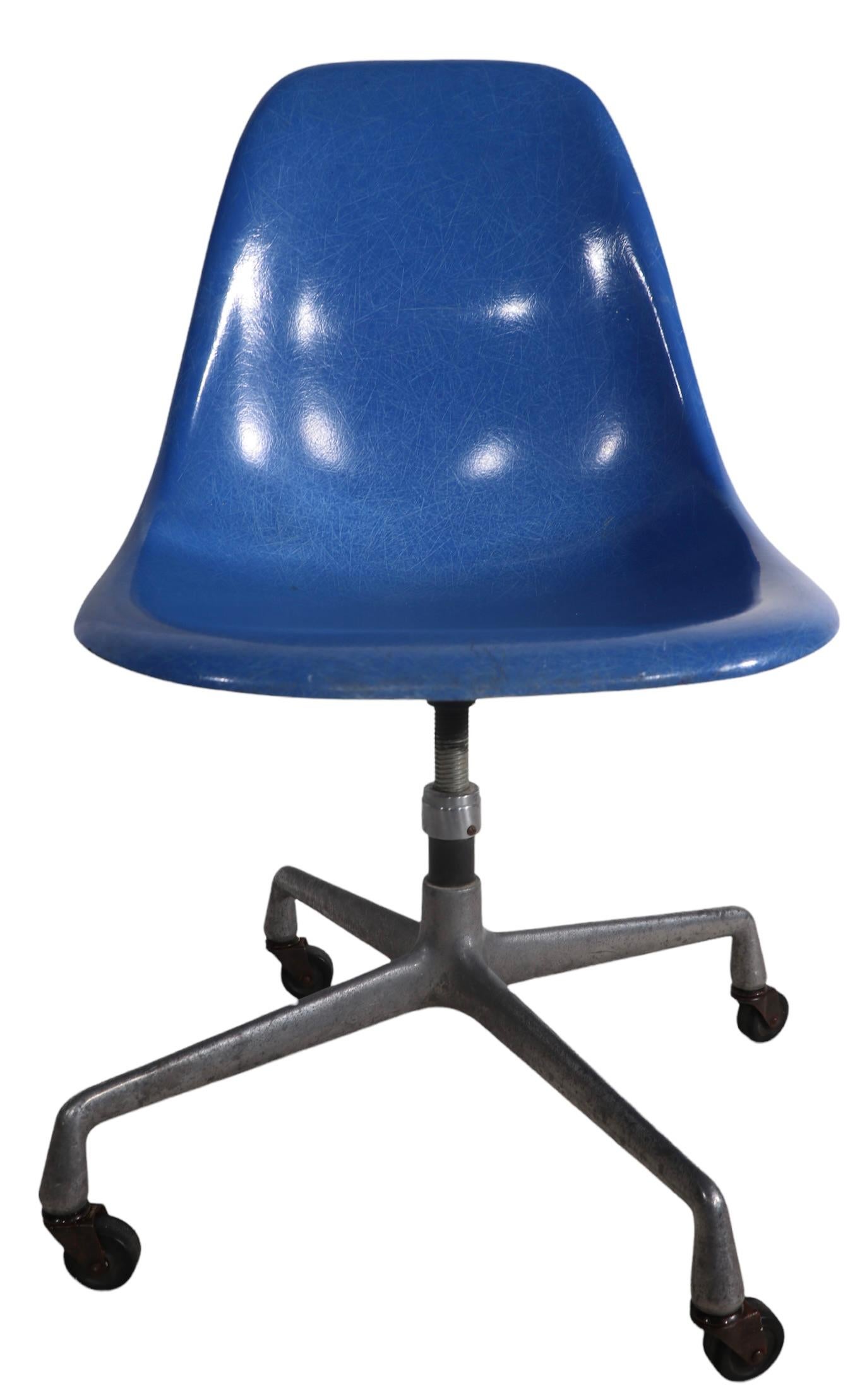 Iconic Eames design, hard to find form, fiberglass shell in blue, on cast aluminum base. This chair swivels, it is adjustable in height, and the base is on wheels, to make this a very flexible and functional chair, in addition to the obvious style