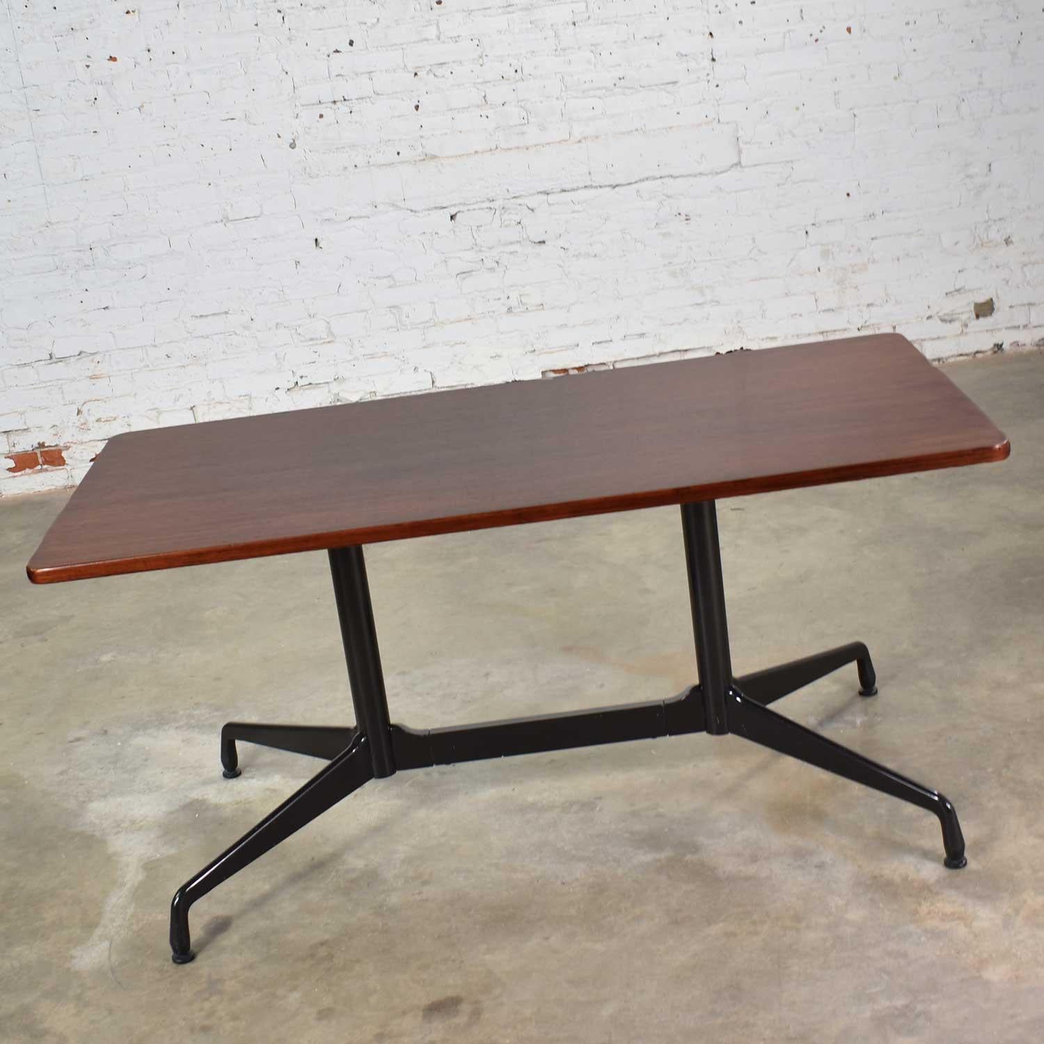 Handsome rectangular conference or dining table from the Aluminum Group designed by Charles and Ray Eames for Herman Miller. This one has a rosewood colored veneer top with black band and a black segmented double pedestal base. It is in wonderful