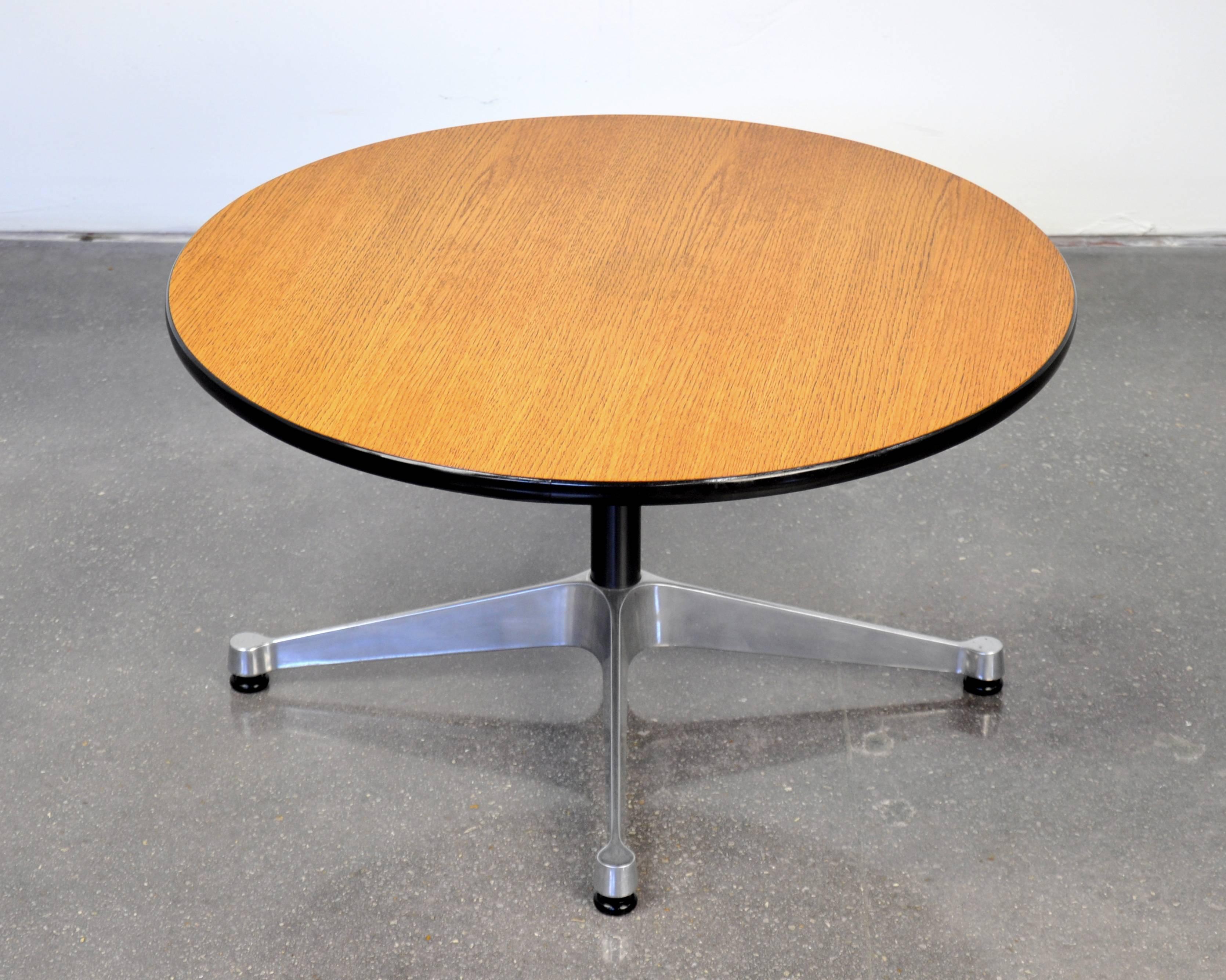 A vintage Mid-Century Modern oak version of the ET307 coffee or cocktail table designed by Charles and Ray Eames for Herman Miller. It features an oak veneer top with black vinyl edge, a black column and a polished aluminum contract base. Also works