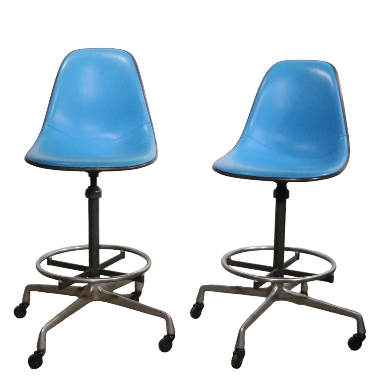 Pair of Eames designed drafting stools, manufactured by Herman Miller circa…
The stools feature vibrant blue vinyl seats, light gray fiberglass shells, gray steel vertical posts, and the classic aluminum universal style base, with original wheel