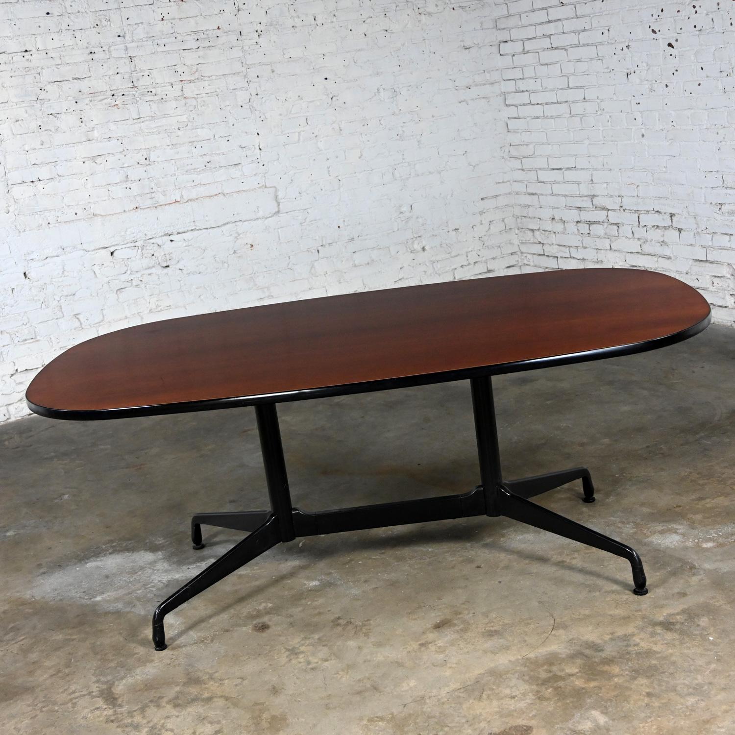 Fabulous vintage MCM (Mid-Century Modern) Eames for Herman Miller racetrack oval conference or dining table with a black universal segmented base and cherry wood veneer top with black vinyl edge banding. Beautiful condition, keeping in mind that