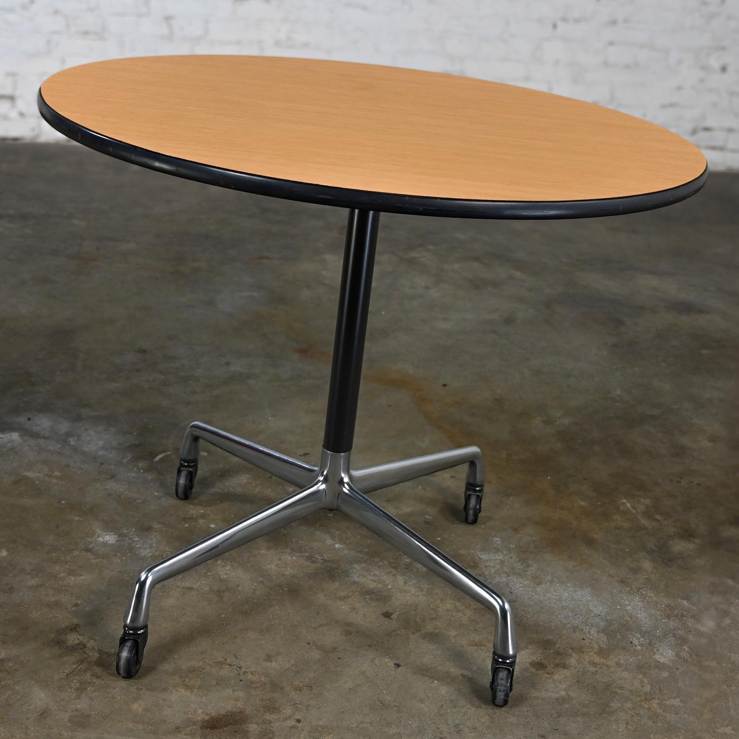 Handsome vintage Mid-Century Modern Eames for Herman Miller table with aluminum universal 4 prong base with black casters, black shaft, aluminum spider attachment, and a 36” round blonde laminate top with black vinyl edges. Beautiful condition,