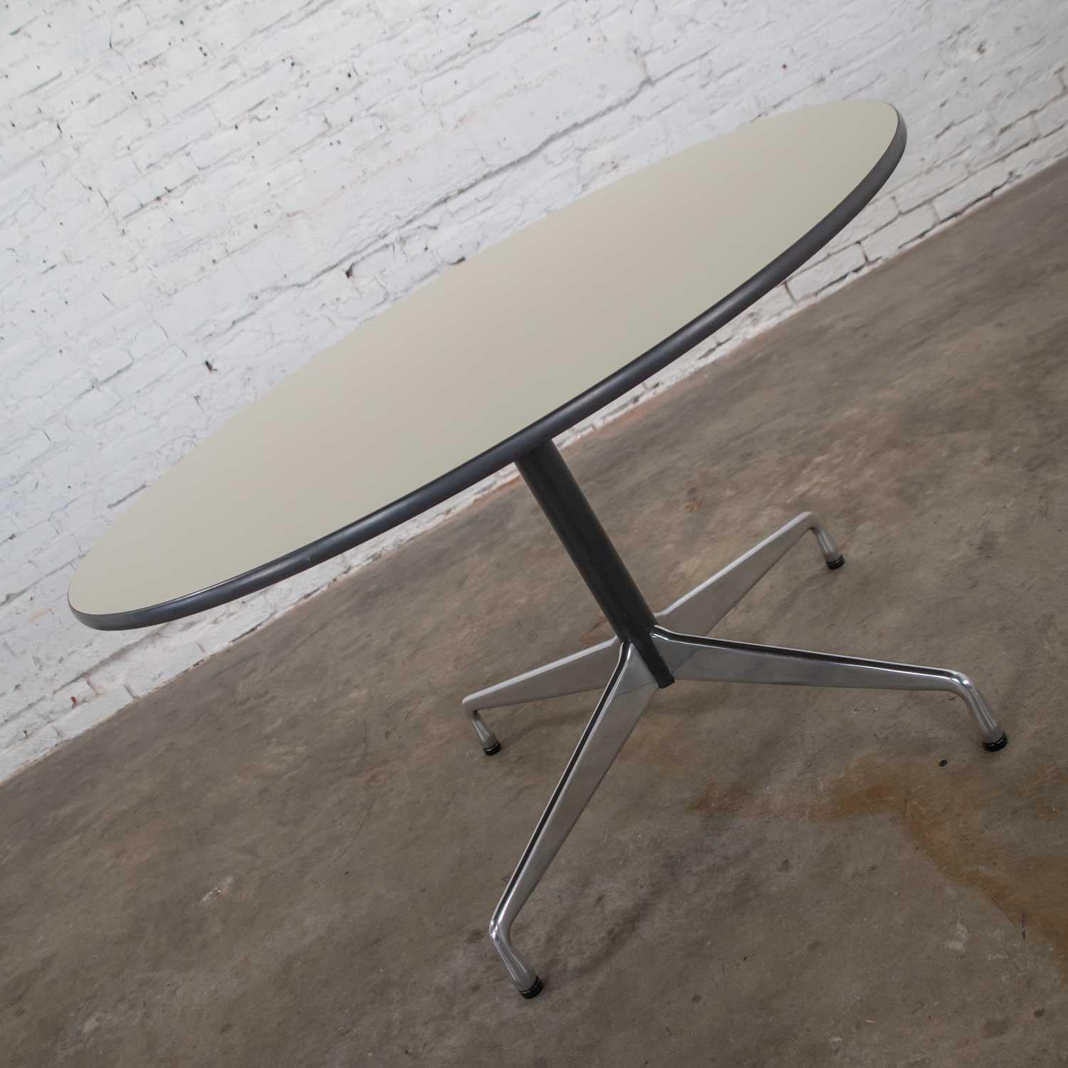 Fabulous Eames Herman Miller round table with the universal base and off-white laminate top with black edge trim and black painted shaft. Wonderful vintage condition. There is a very small nick on the edge of the white laminate but does not detract