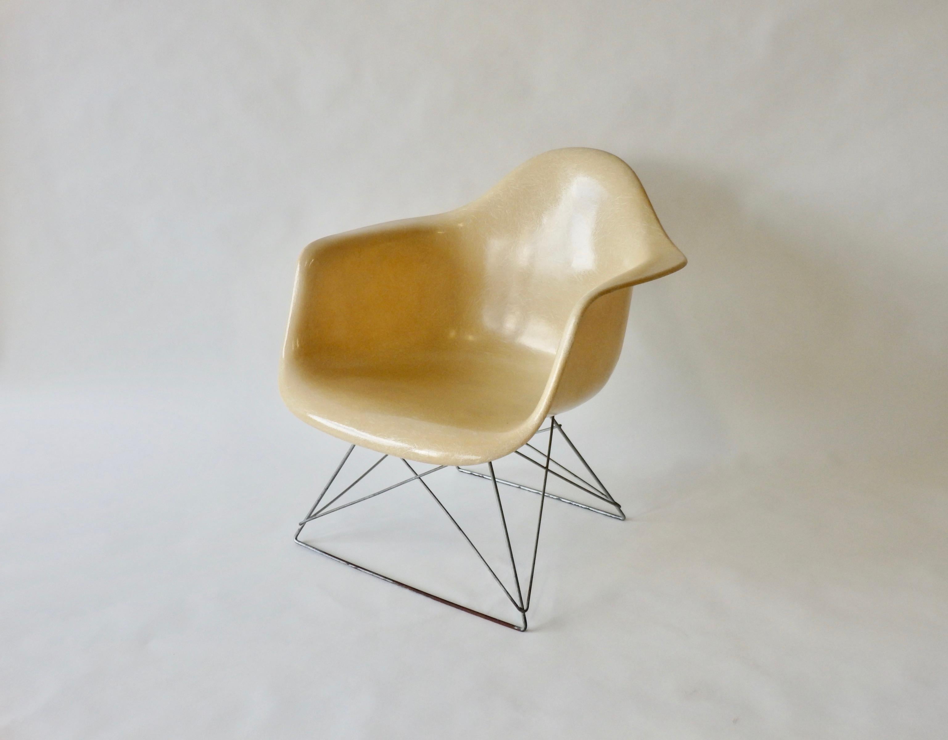 From the fiberglass chair series developed by Charles and Ray Eames immediately after WW2. Widely distributed by Herman Miller. This low arm rod (LAR) chair has zinc finished base with butter cream white fiberglass arm shell. Patina to base. Shell