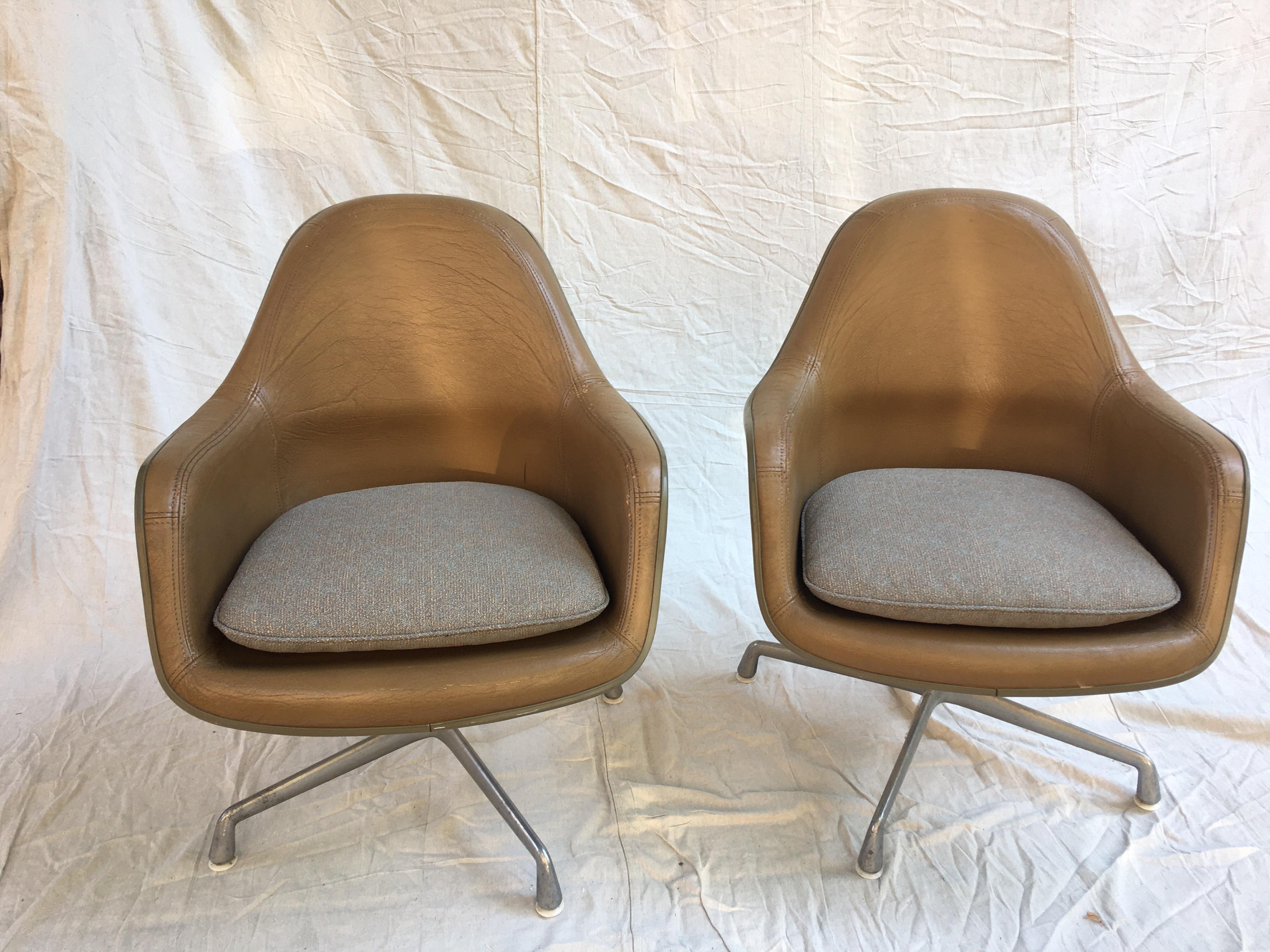Eames for Herman Miller high back leather lounge chairs. Uncommon pair with aluminum group bases and fiberglass seats. Leather is in good shape with 1 repair on each arm as seen in photos. Chair swivel and seat pads have been re-upholstered.