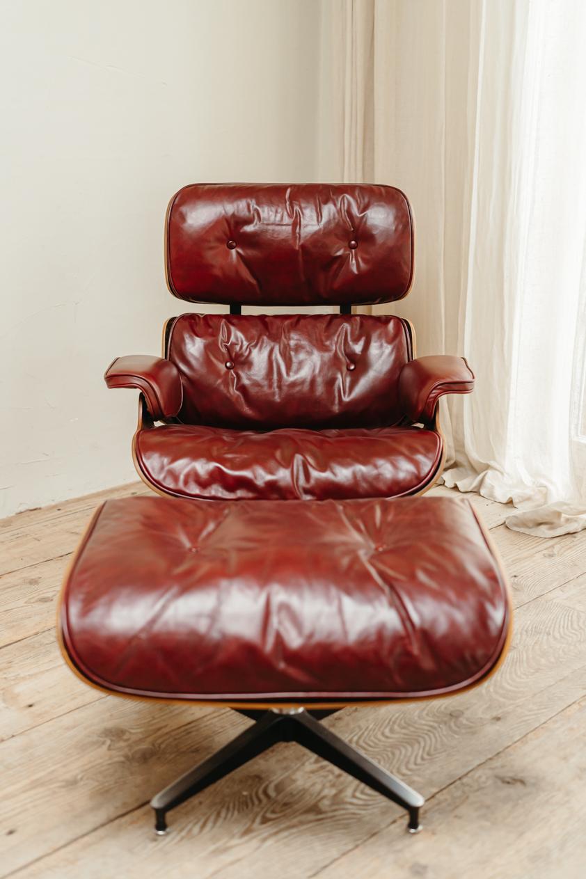 lovely patinated burgundy red leather on this classic Eames lounge chair and its ottoman, completely restored, dated 1965, dimensions ottoman are 66 cm wide 45 cm high and 53 cm deep, dimensions lounge chair are 88/40 cm high x 85 cm deep and 85 cm