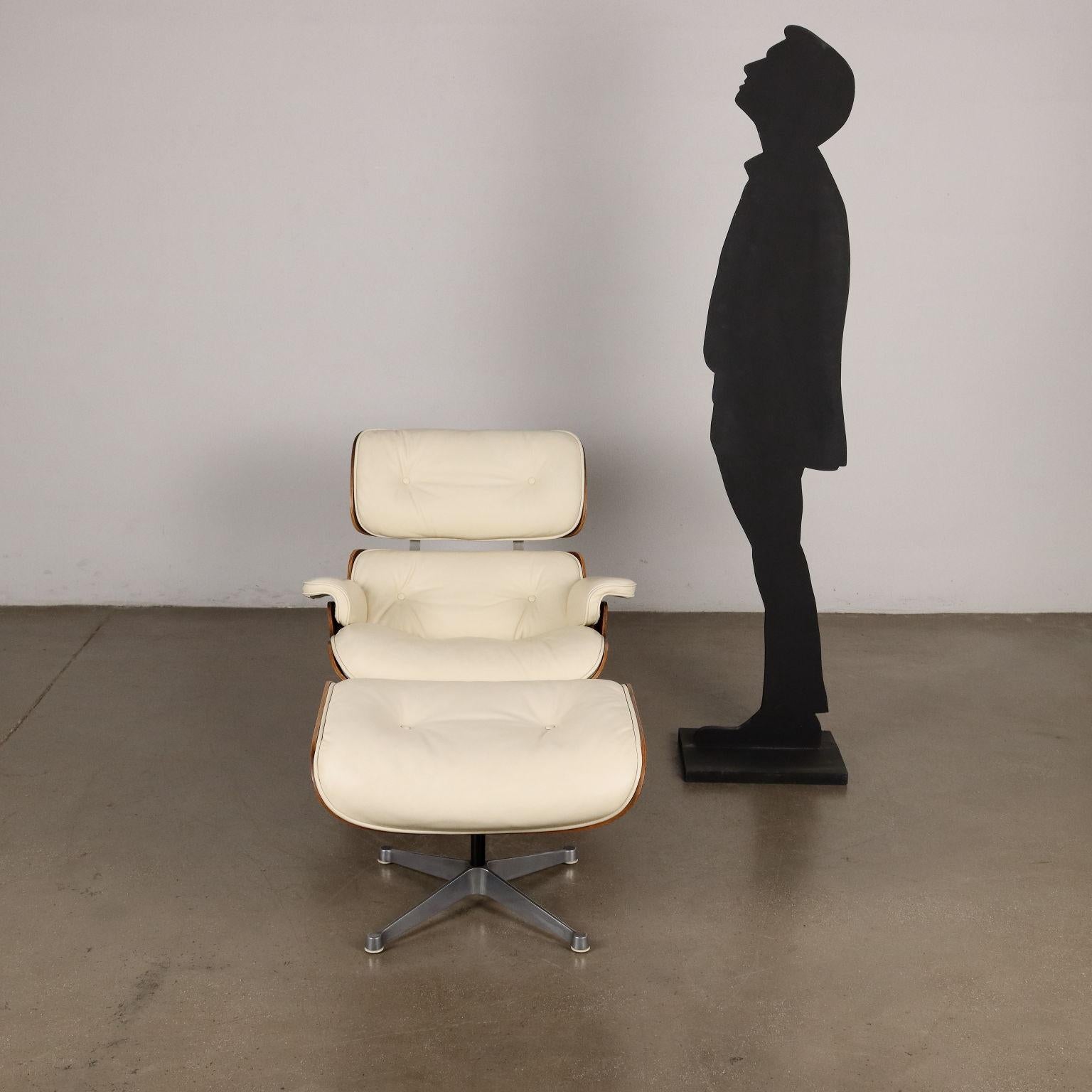 Iconica poltrona girevole con pouf disegnata da Charles Eames e prodotta da Herman Miller. Presenta la base in alluminio smaltato, la scocca in legno esotico, l'imbottitura in espanso e il rivestimento in pelle bianca. In ottime condizioni originali