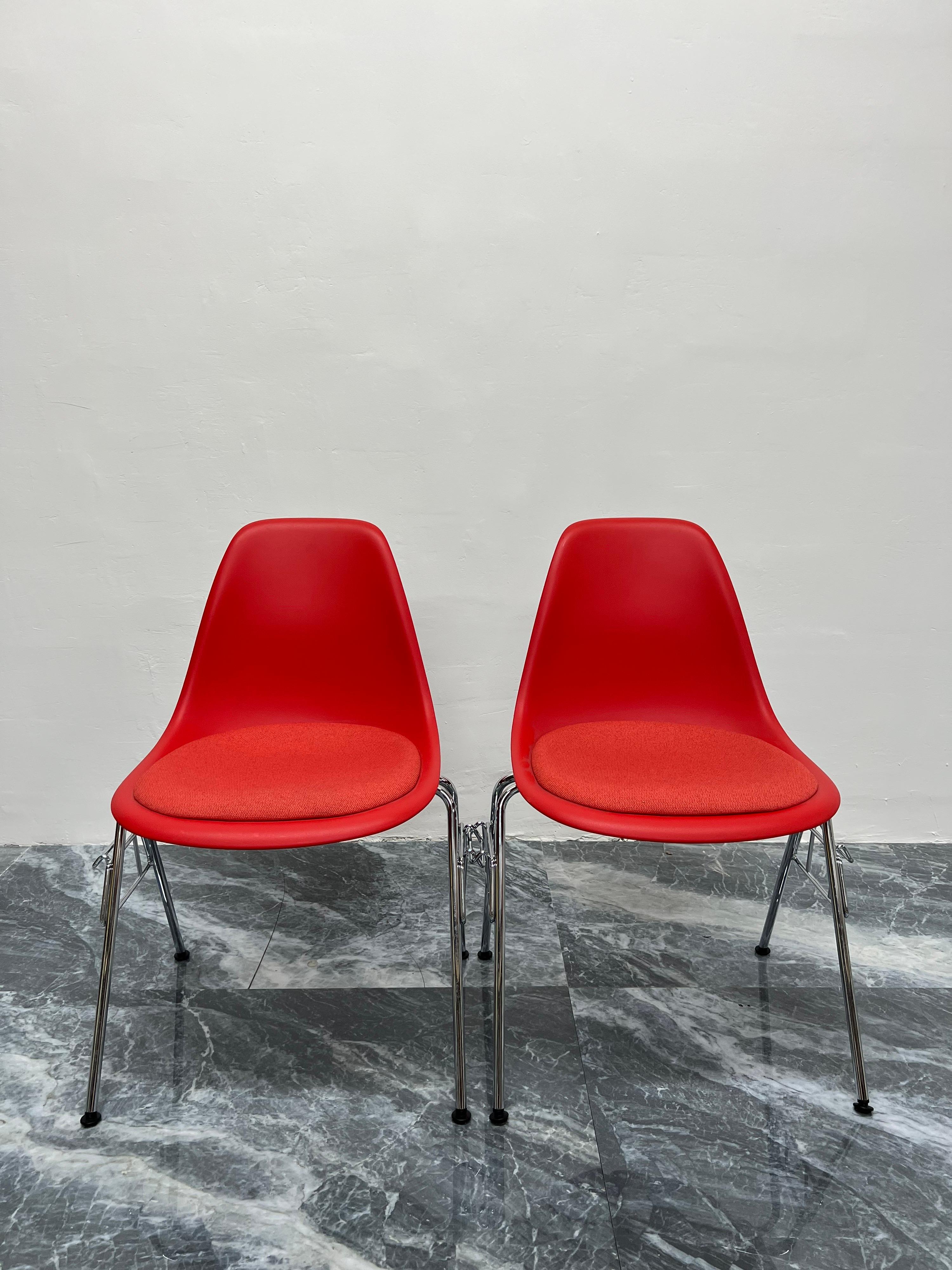 Stackable and interlocking molded eco friendly plastic shell side chairs with upholstered seats and chromed steel legs by Charles and Ray Eames for Herman Miller.