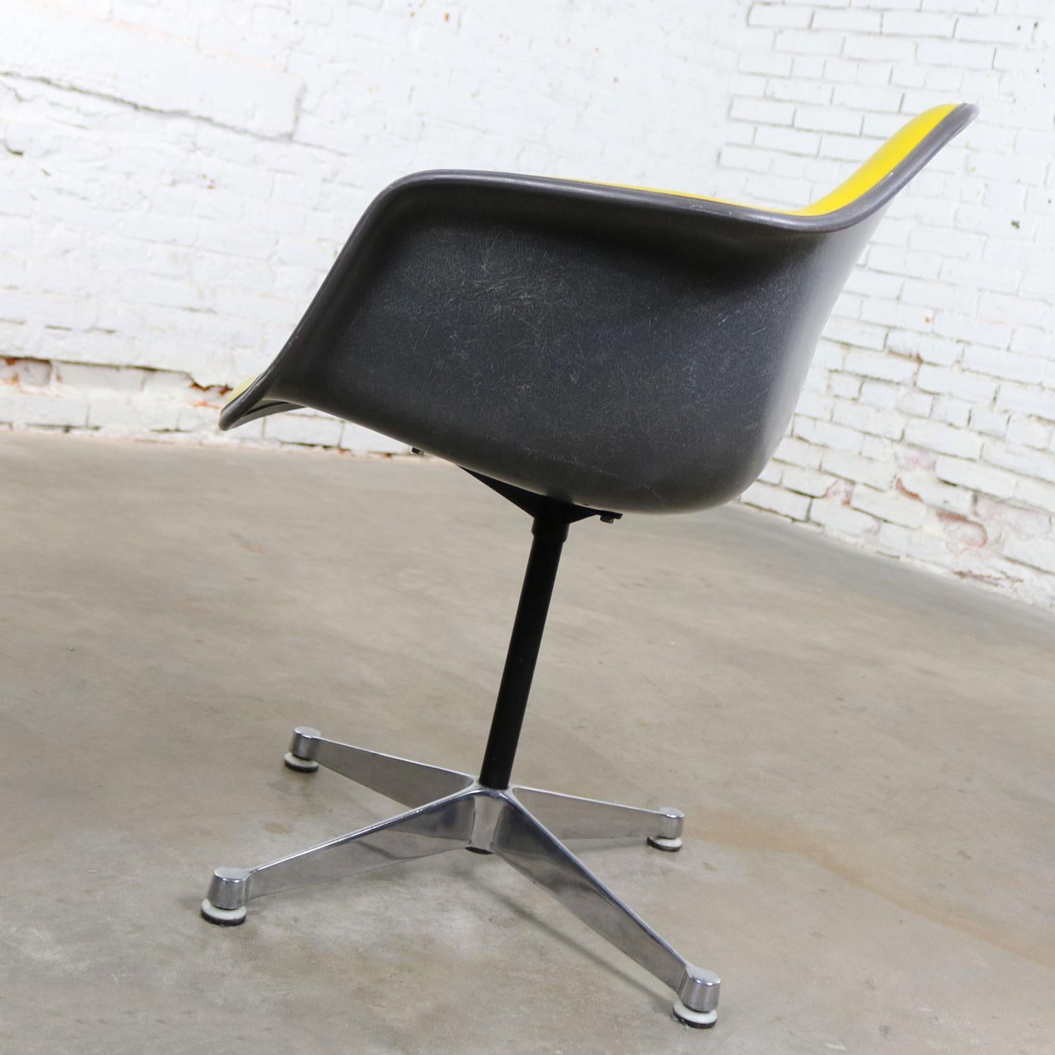 Iconique fauteuil vintage Eames, pivotant sur base en aluminium moulé, avec siège pivotant rembourré en Naugahyde jaune sur coque en fibre de verre grise. Il est en très bon état. La base à quatre branches en fonte d'aluminium est finement polie et