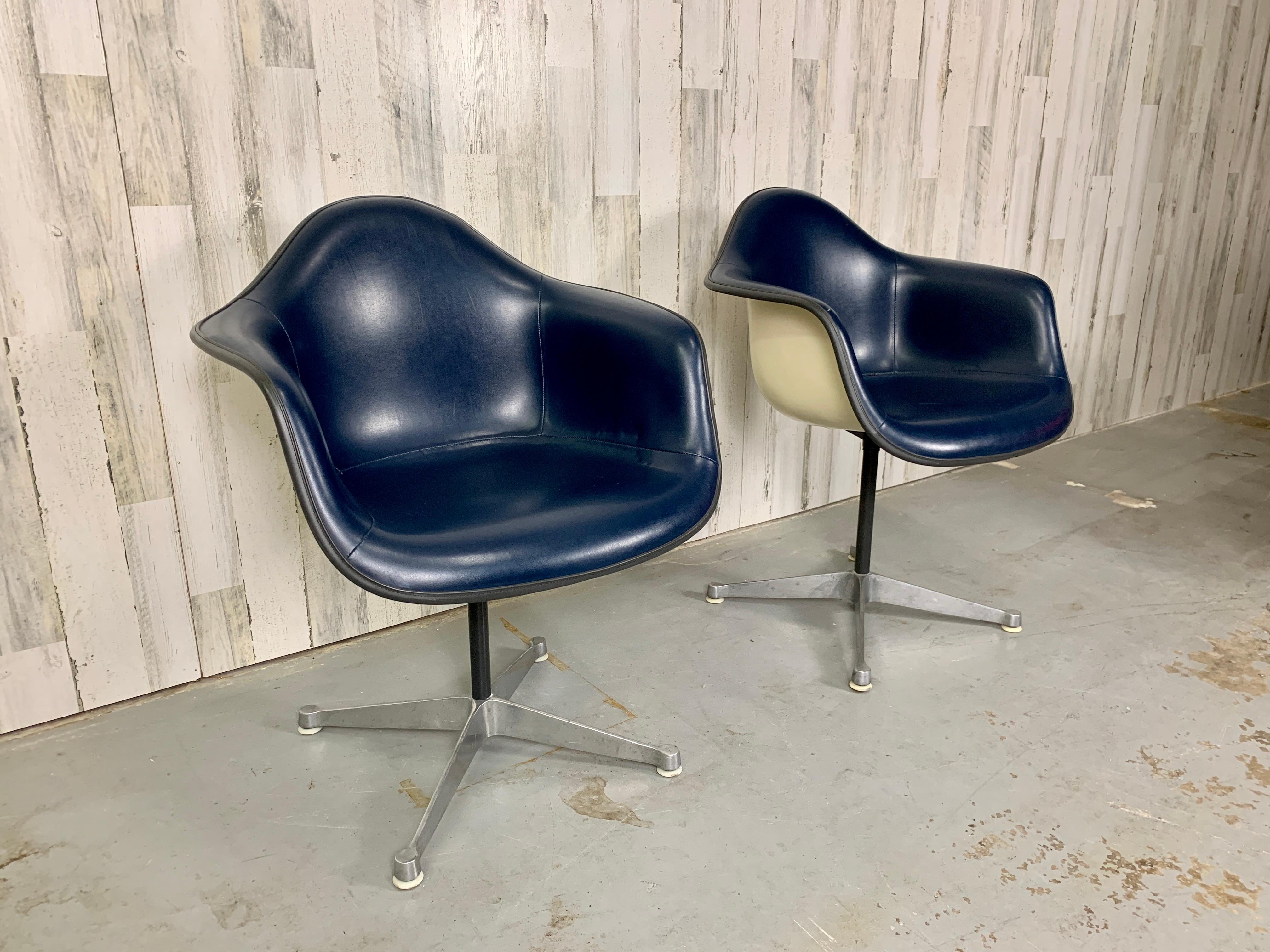 Iconic Eames for Herman Miller fiberglass shell chairs with original dark blue vinyl padded upholstery.