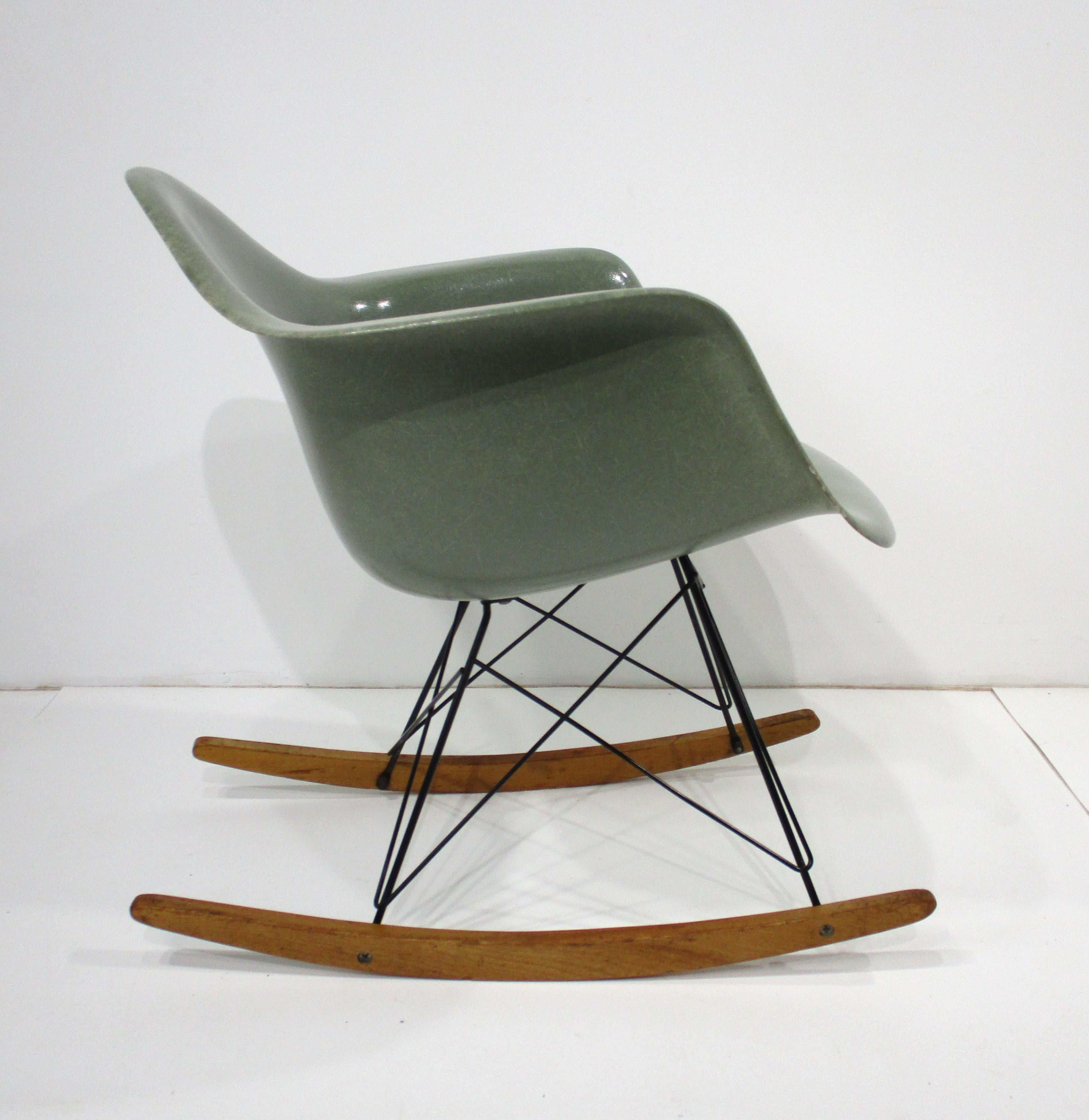 A rare seafoam green molded fiberglass rocking chair with black metal wire base mounted on birch runners . This iconic piece was designed by the husband and wife team of Ray and Charlies Eames who's Mid Century furniture is as fresh today as it was