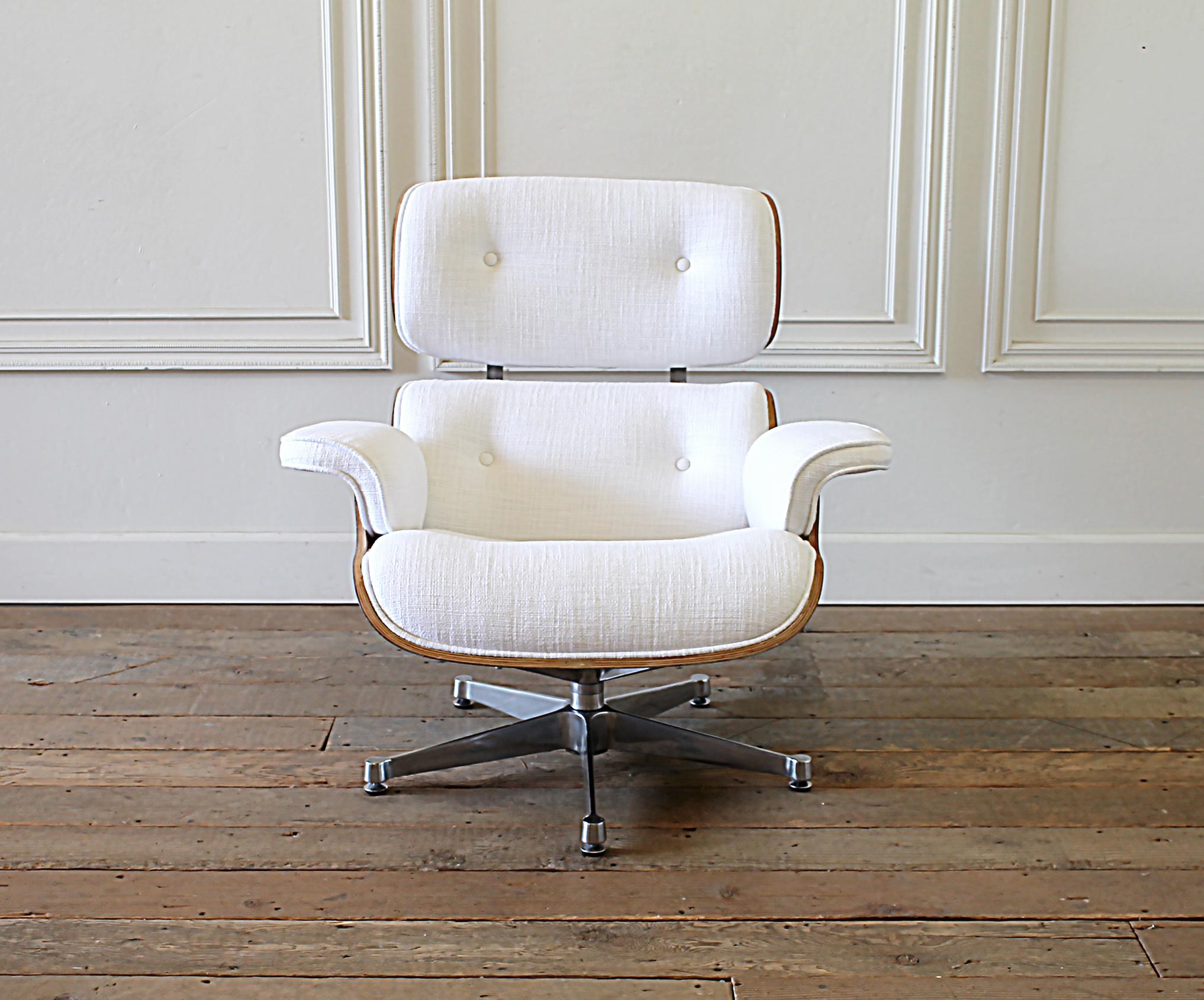 Eames style chair and ottoman in coated white linen blend upholstery.
Brand new upholstery, with light wood, and stainless base.
Subtle scuffs are present on the wood and base.
White thick nubby textured linen with coat to protect from everyday