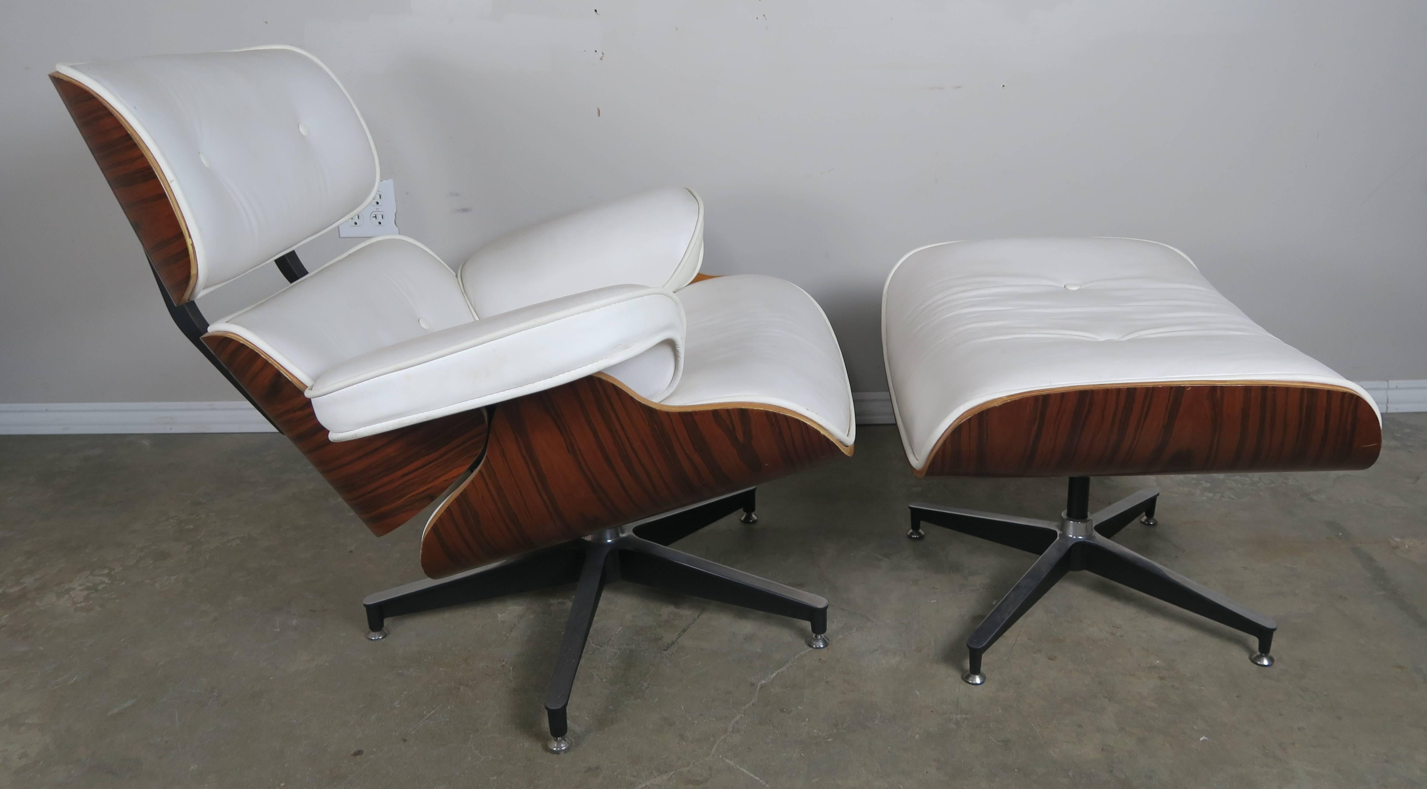Vintage 1970s Herman Miller Eames style lounge chair and ottoman in rosewood. Upholstered in original white leather that is still in excellent condition. Aluminium base.