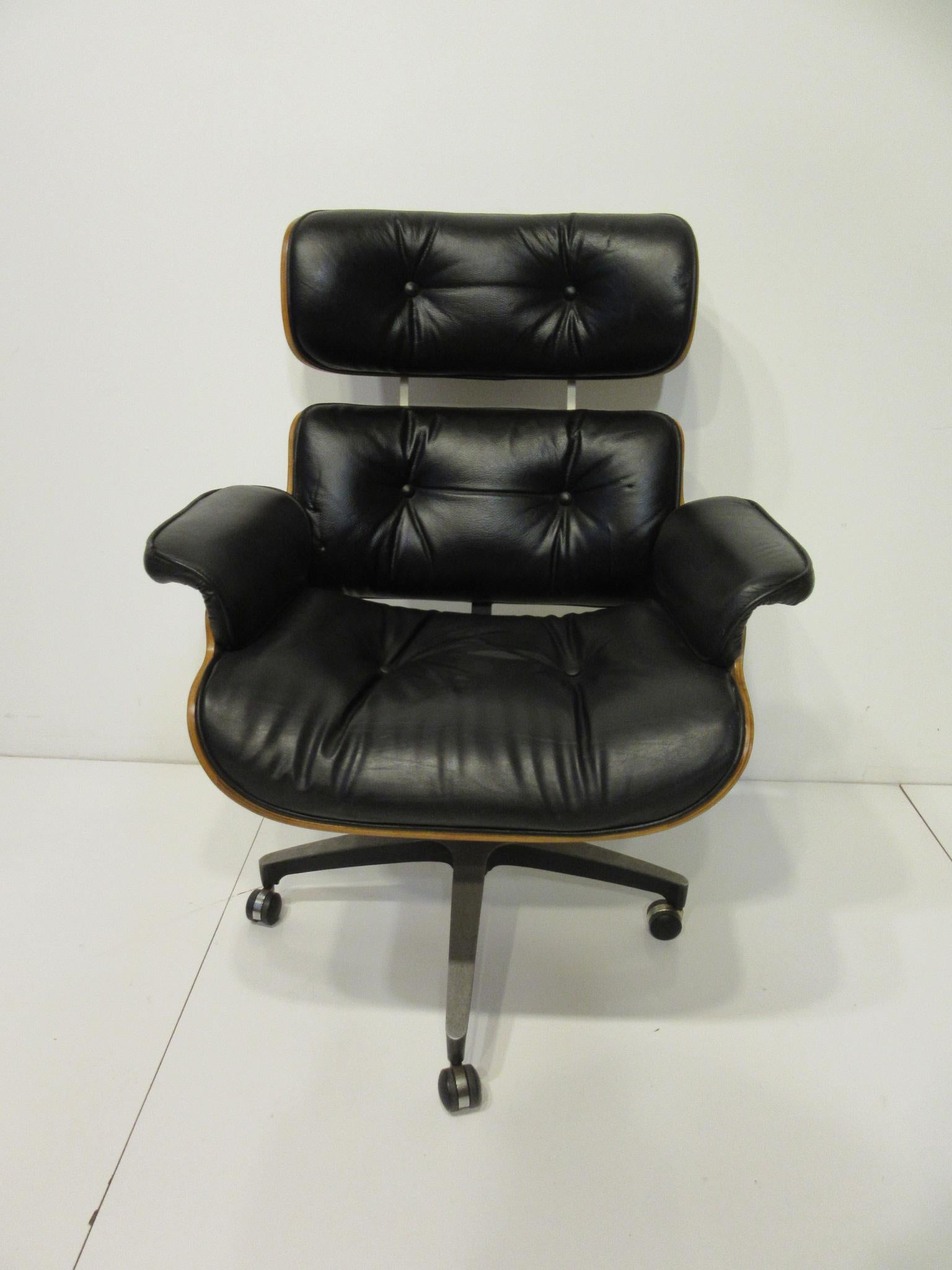 A super comfortable Eames styled black leather and walnut bodied rolling desk chair that looks like a Herman Miller 670 lounge chair. This chair has an adjustable height for any desk fit and bottom seat spring for comfort and a cast star aluminum
