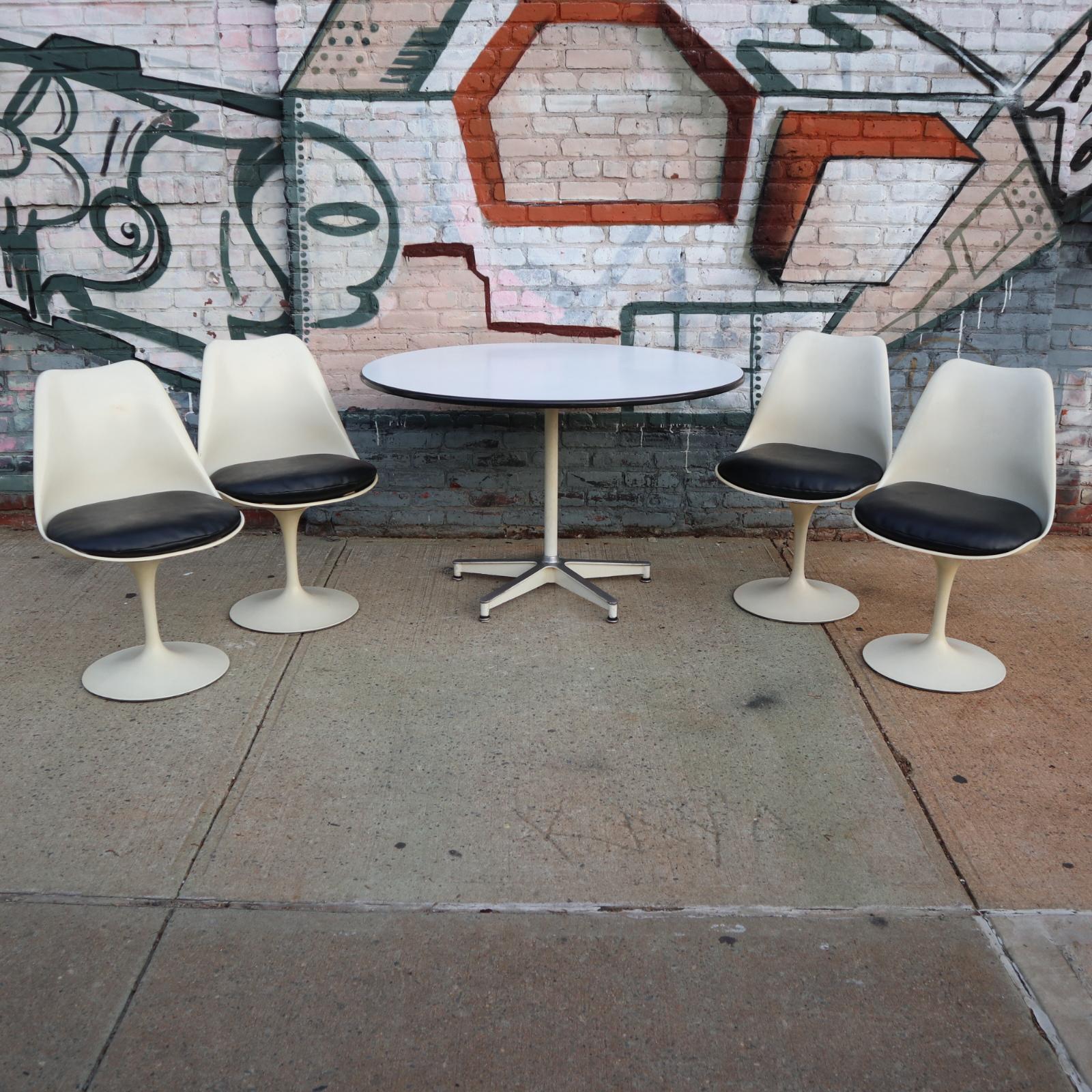 Featuring 2 of the best American designers of the 20th century, this dining set is comprised of 4 signed Knoll tulip chairs paired with a Herman Miller dining table. Table is model 650, featuring white laminate top in excellent condition resting on