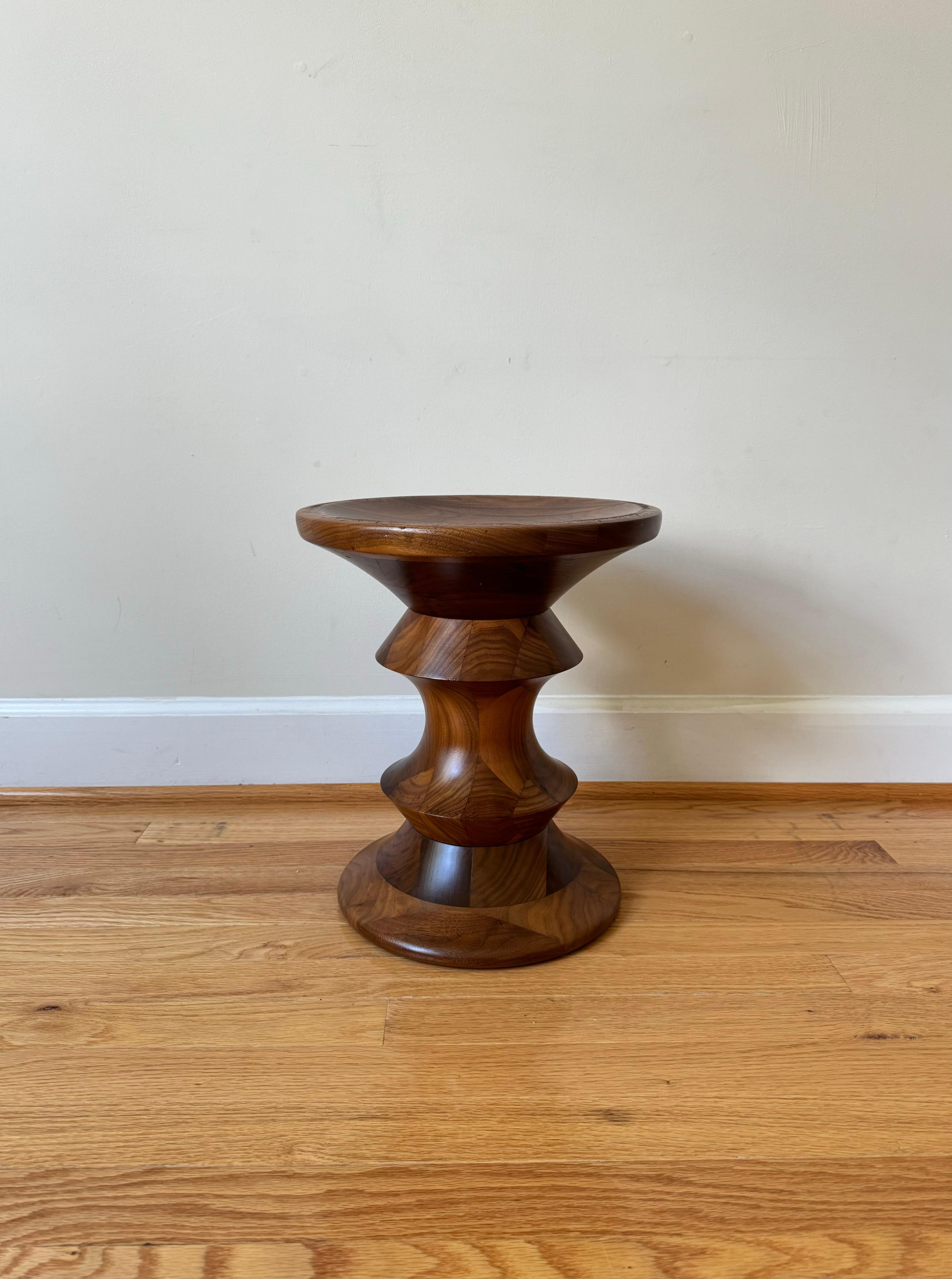 The Eames Walnut Stool series were designed by Ray Eames in 1960 for the lobby of the Time-Life building in New York City. Crafted from solid turned walnut featuring concave tops and bottoms, these striking sculptural pieces can function as both