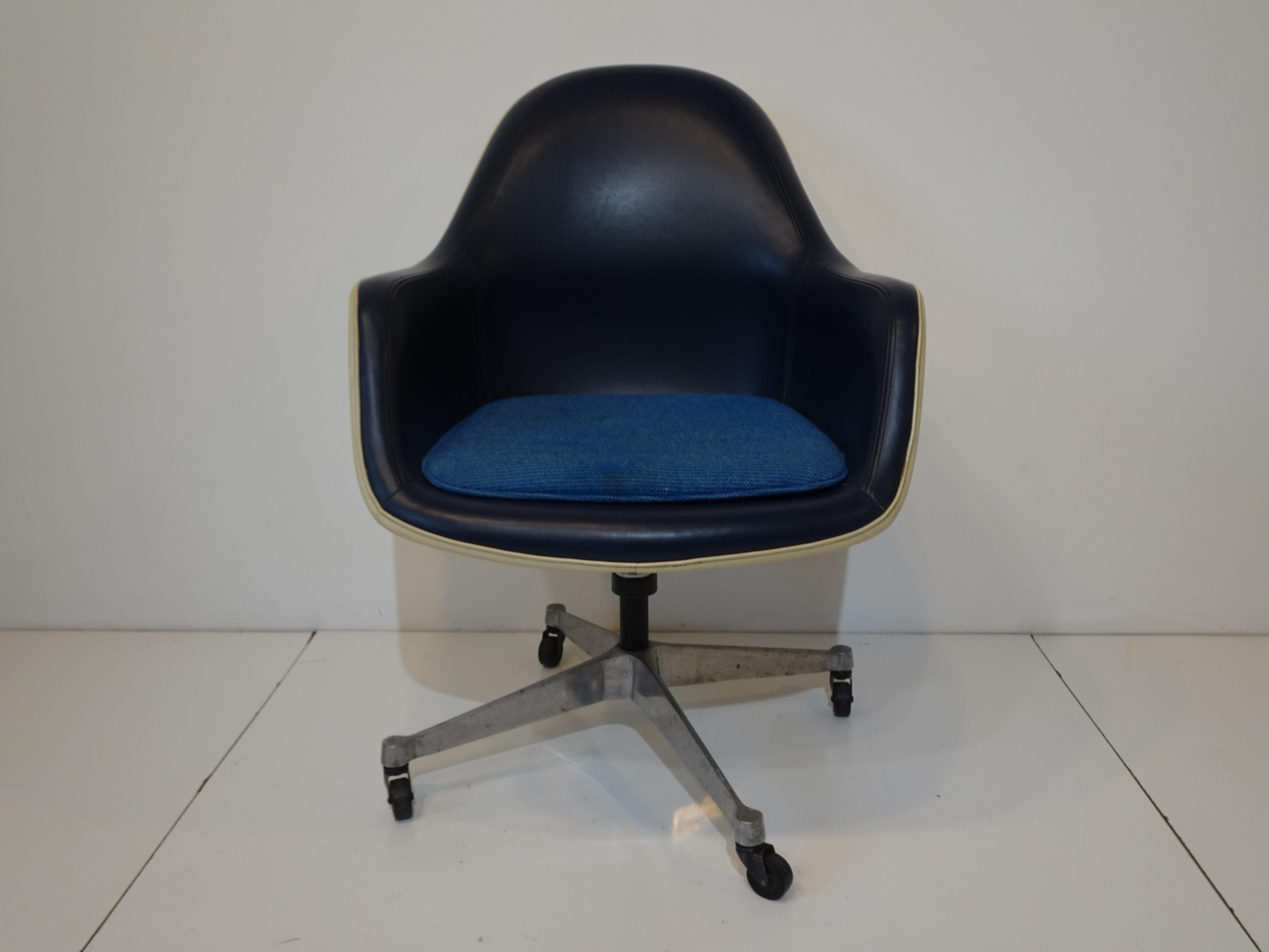 A hard to find rare Eames rolling high back desk arm chair with white fiberglass shell, dark blue Naugahyde upholstery and lighter blue seat pad . The star base is in cast aluminum with black rubber wheels and is adjustable manufactured by the