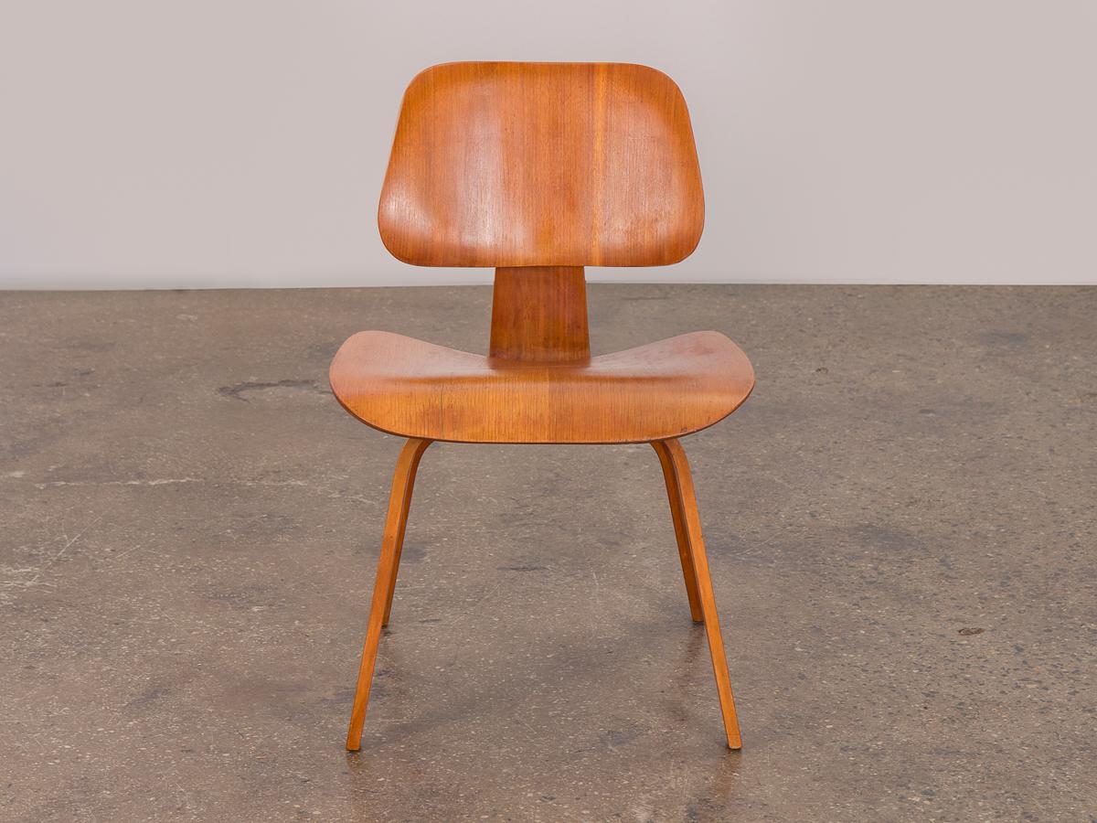 Gleaming walnut Eames DCW dining chair wood for Herman Miller. Molded chair boasts curving planes in this iconic midcentury design. This early example is from the 1950s, and is in excellent condition owning the original shock mounts and five screw