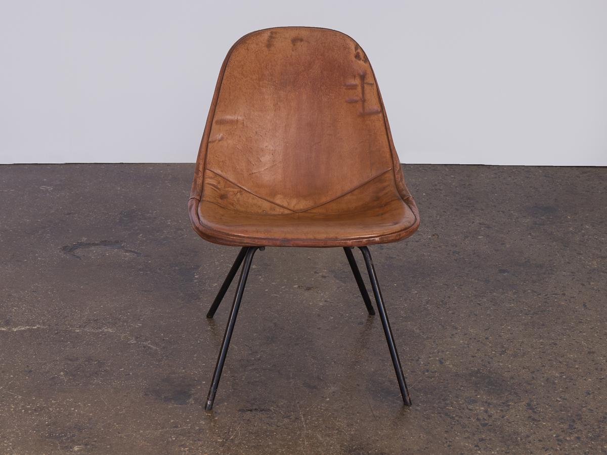 An exemplary variation of an otherwise definitive design, this Eames wire chair sits on a low lounge height base. It features original leather in a gorgeously aged patina. The rich, smooth, coffee colored leather fosters a cohesive contrast with the