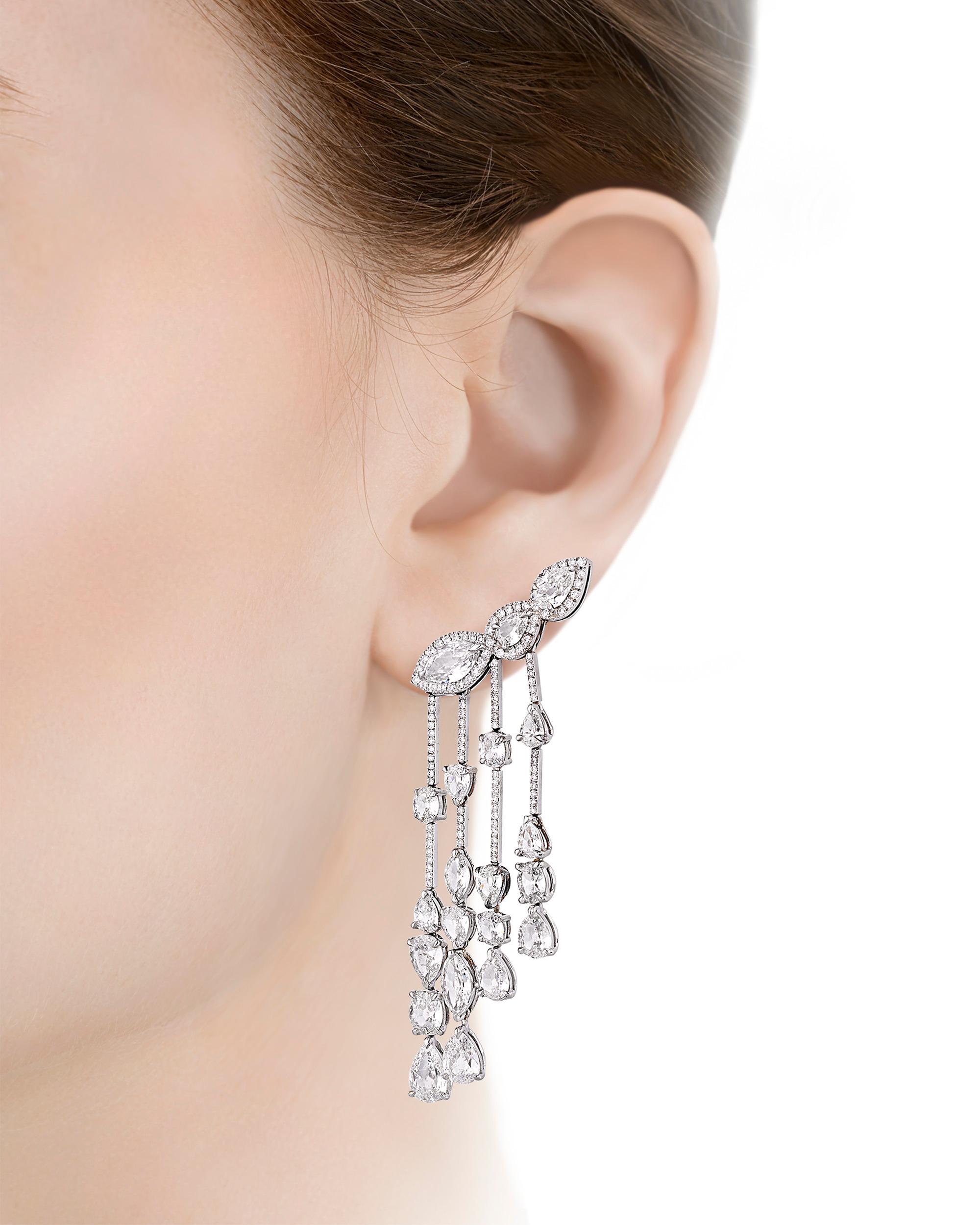 A cascade of diamonds dangle from this one-of-a-kind pair of Italian earrings. The ear climber design of the duo features approximately 16.44 total carats of white diamonds in a variety of fancy shapes and sizes that make a dazzling impact. Set in