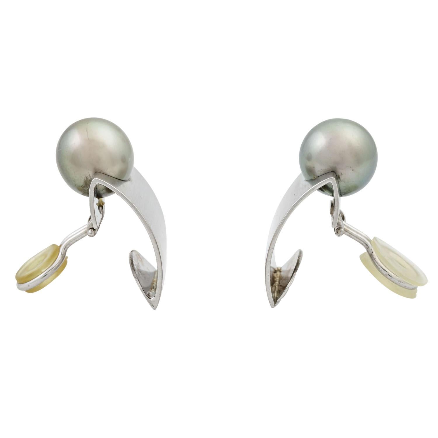 convex rectangular shape made of matted WG 18K, each with a fine silver-grey cultured pearl approx. 11.5 mm, 22.4 g, 20th/21st Century, slight signs of wear, nice workmanship, with maker's mark. (15)

 Earclips with silvergrey Tahitian cultured