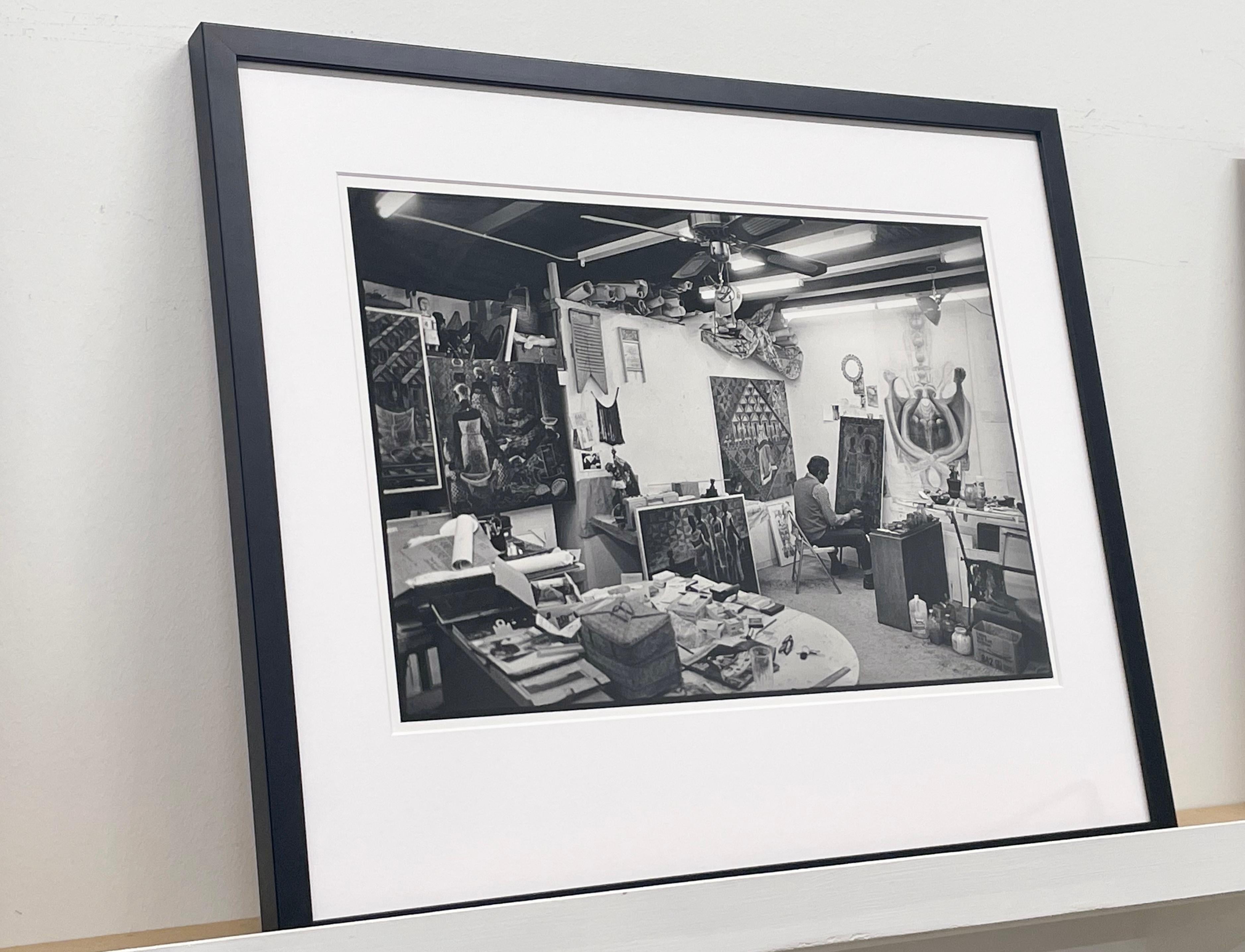 John Biggers dans son Studio par Earlie JR représente John Biggers en train de peindre dans son studio d'art, entouré de tableaux et de fournitures artistiques. 

Tirage gélatino-argentique
Format du papier : 20 x 16 pouces, Format de l'image :