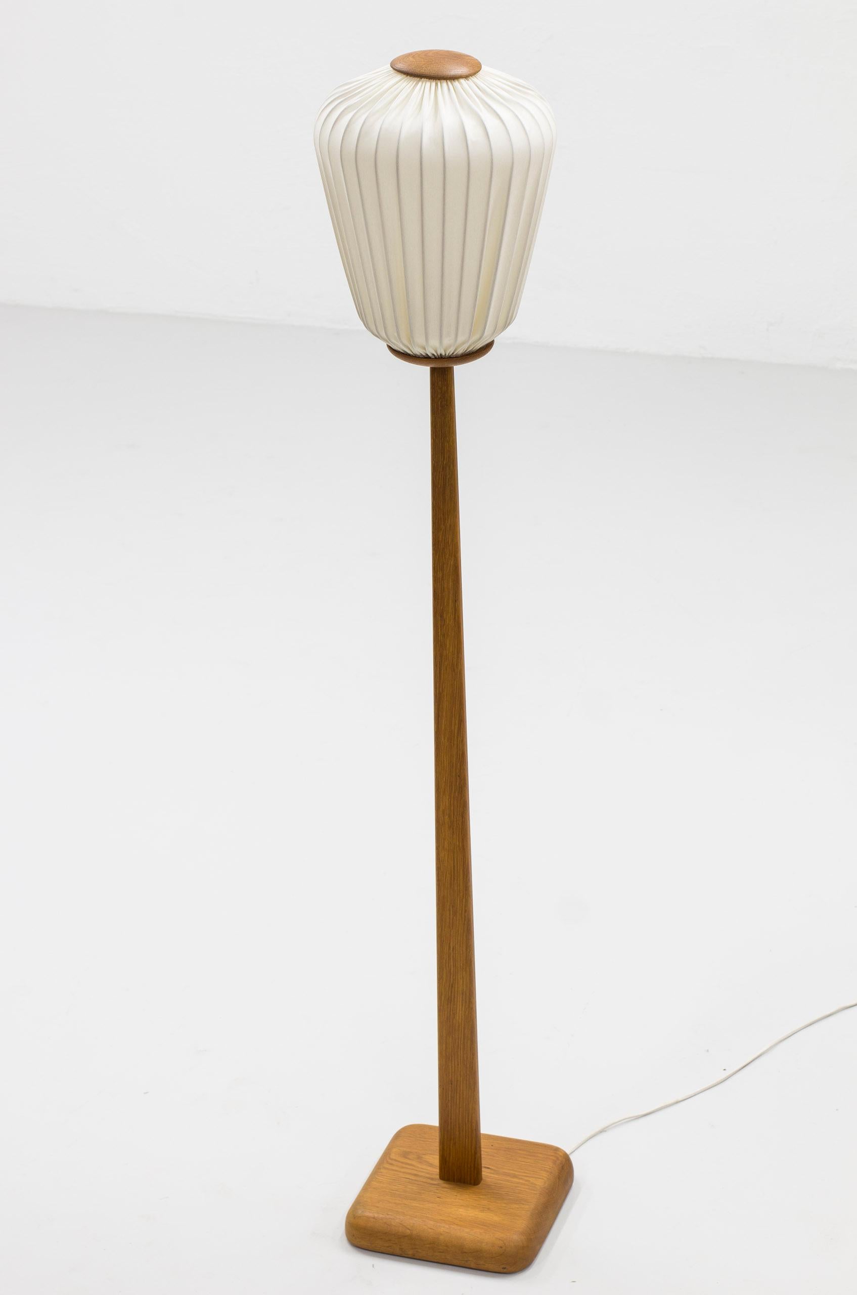 rare and early floor lamp designed by Uno & Östen Kristiansson. Produced in Sweden by Luxus during the 1950s. Made from solid oak with shade in creme colored cotton. the shade has been reupholstered, hand sewn in chintz fabric. Very good vintage