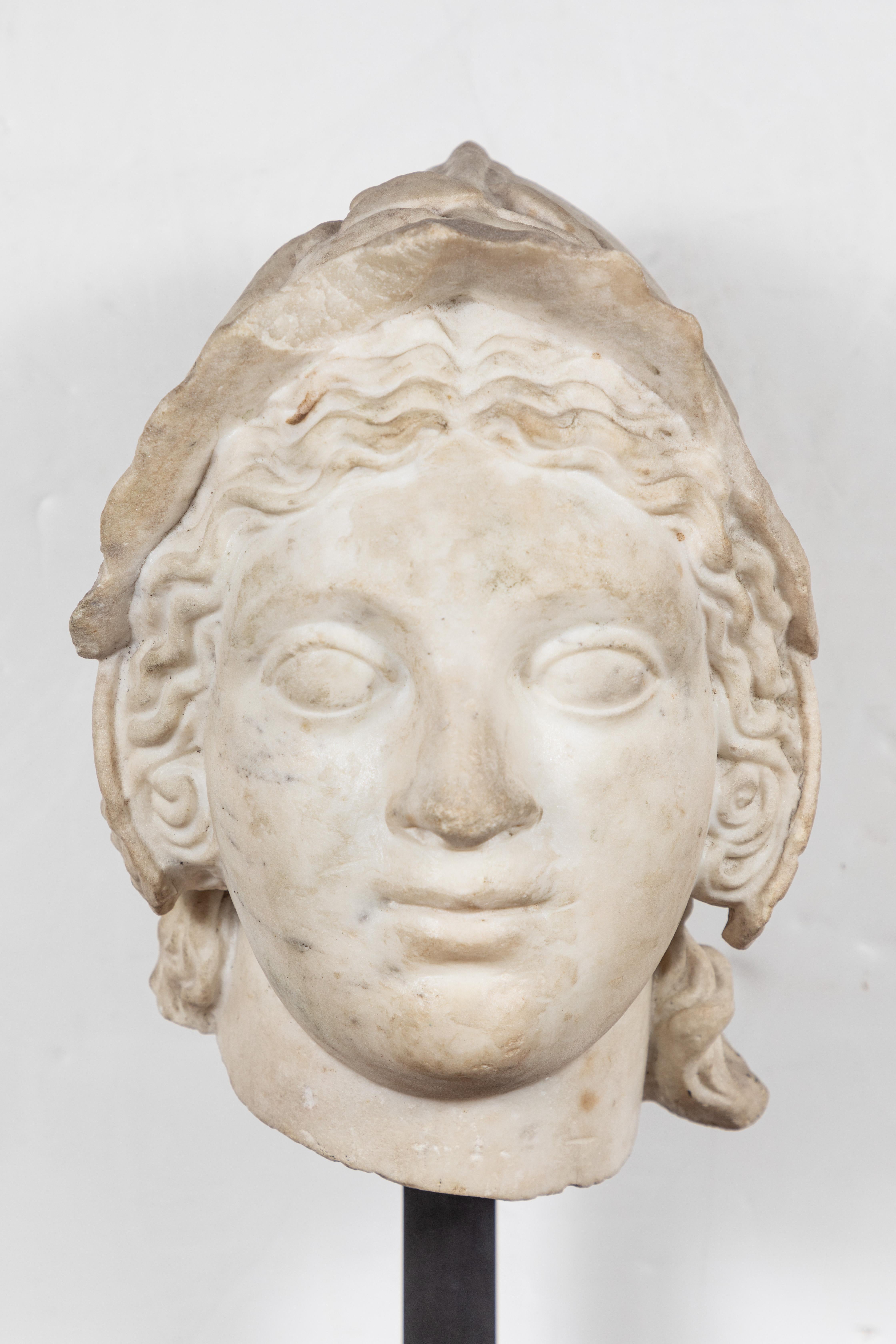 Exceptional, hand carved all the way around, 17th century, Carrara marble bust of Athena in a helmet surrounded by a laurel wreath. Fabulous expression, and beautifully carved. Mounted on a beautiful, later, tiered stone base.

Dimensions of bust