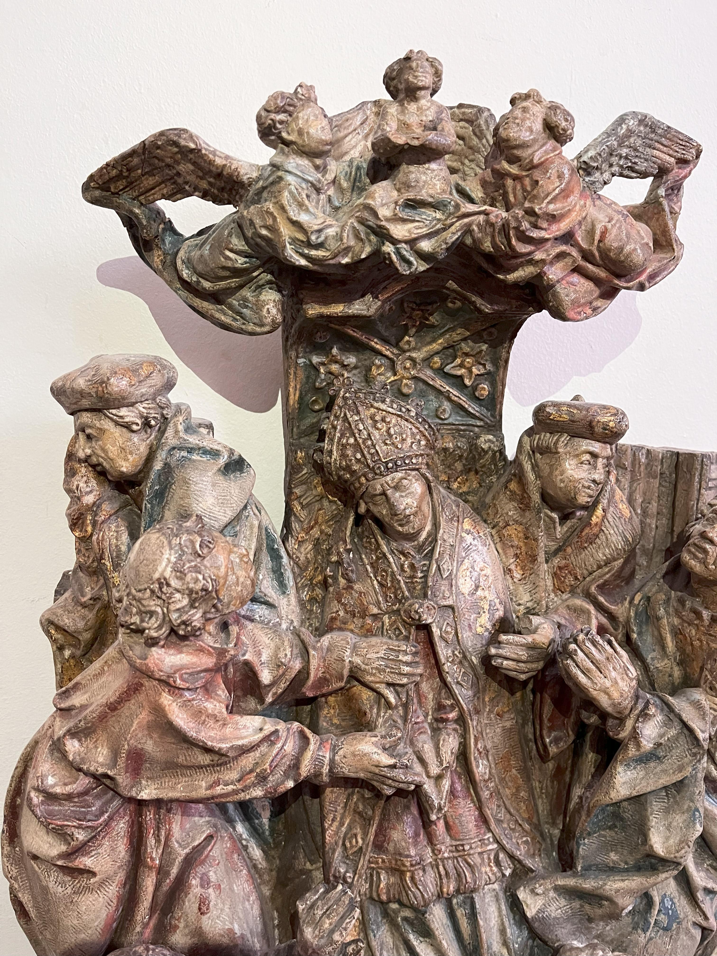 An Early 16th Century Stone Carving with polychrome : 'The Death of a Prelate'. The enthroned figure of a Bishop surrounded by attendants and surmounted by celestial angels.  