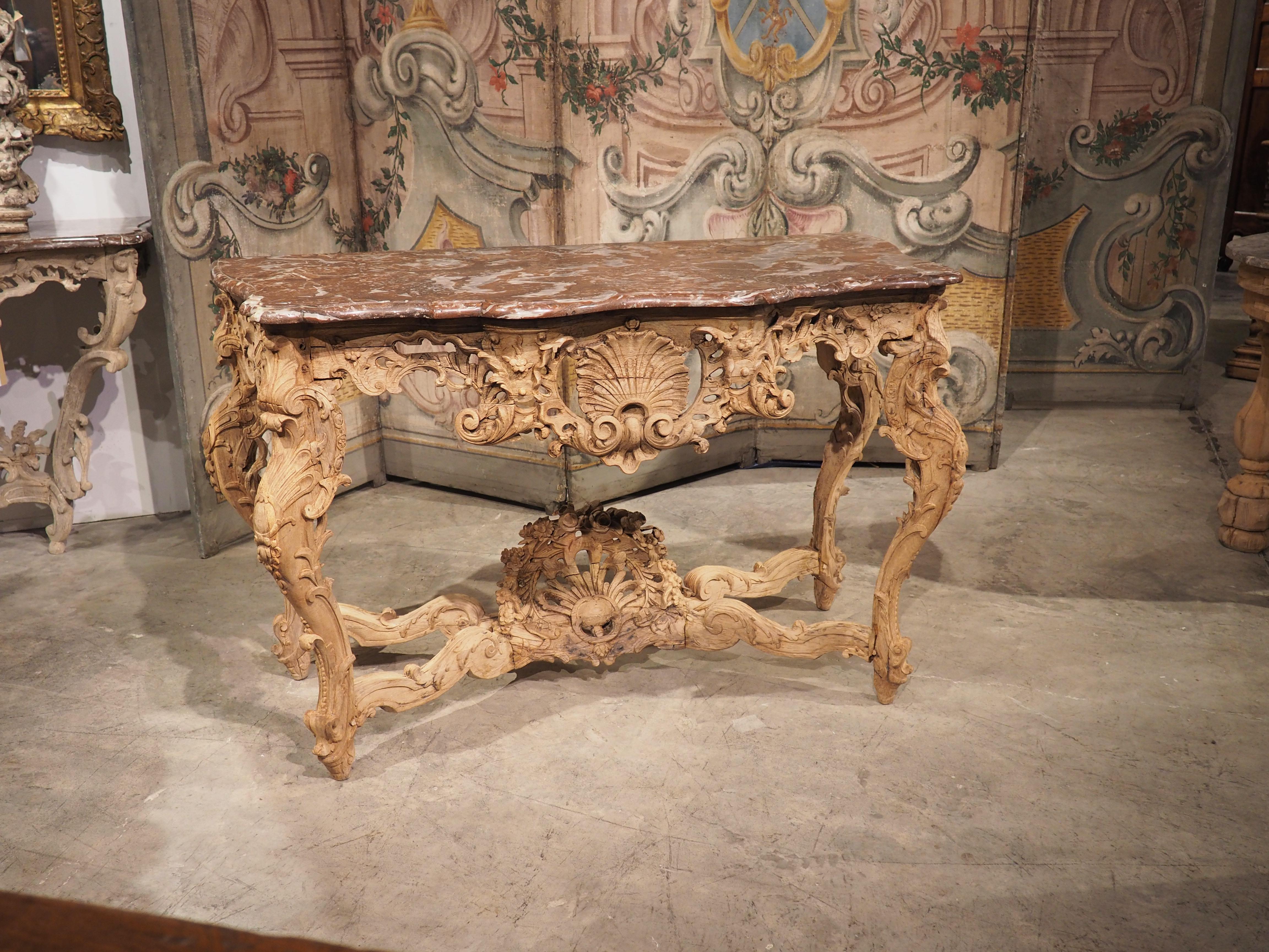 A period Regence piece, this elegant console table was hand-carved in the Paris region (Ile De France) in the early 1700’s. At some point in its history, the wood has been stripped, leaving traces of the original finish amid the stunning oak grain.