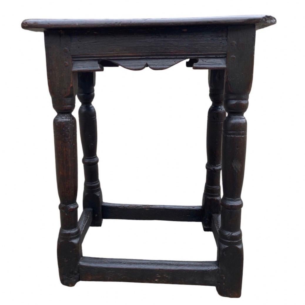 Charles I joint stool made in England in the early 1600s using oak. This is a beautiful and old stool that has lived a very long time and has a lot of stories to tell. The top shows a single board (with some cracks and a corner missing) with ogee