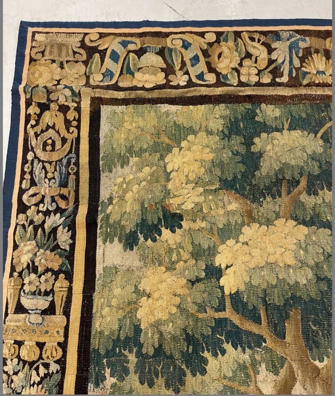 This is a gorgeous antique Early 17th century Flemish Verdure landscape tapestry depicting a beautiful and rich summer scene of a countryside with lush trees and vegetation, and birds with ornate gardens and a castle in the distance. The border