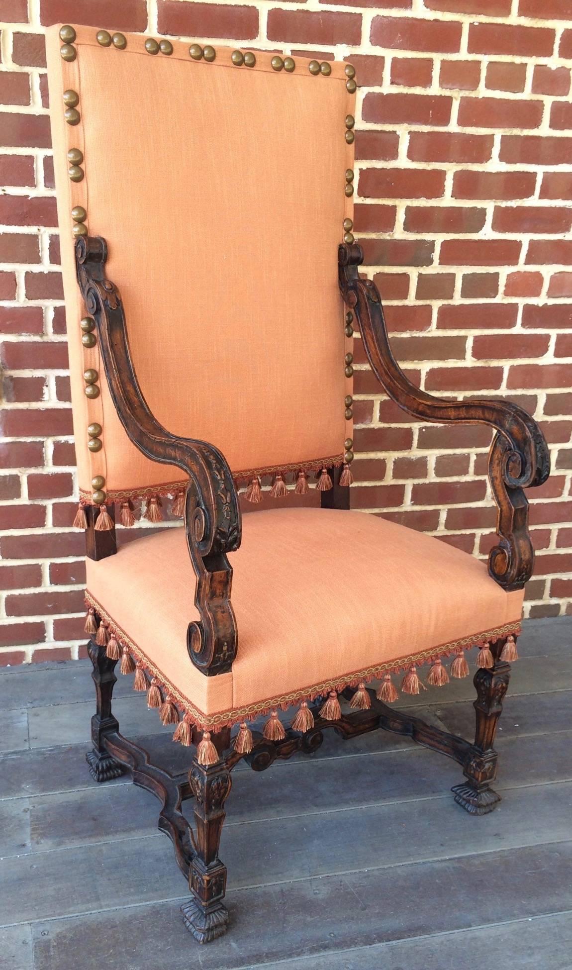 A wonderfully early form of a 17th century French Provincial Louis XIII period armchair. This Classic hall chair has a rectangular back and is made of deeply patinated Circassia walnut. The downward sweeping curved arms and bell flower decoration