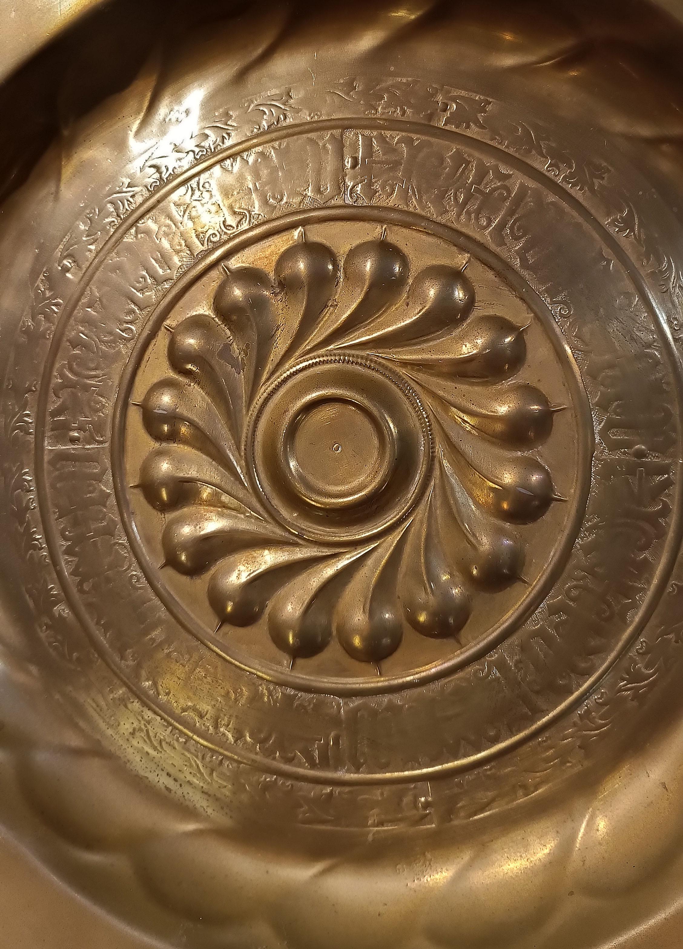 Splendid pair of embossed brass almoners. The brim is flat, adorned with a thin engraved stylised decoration, while the umbo is raised and decorated with an oblique engraved pod motif. Furthermore, the umbo is surrounded by a band with an