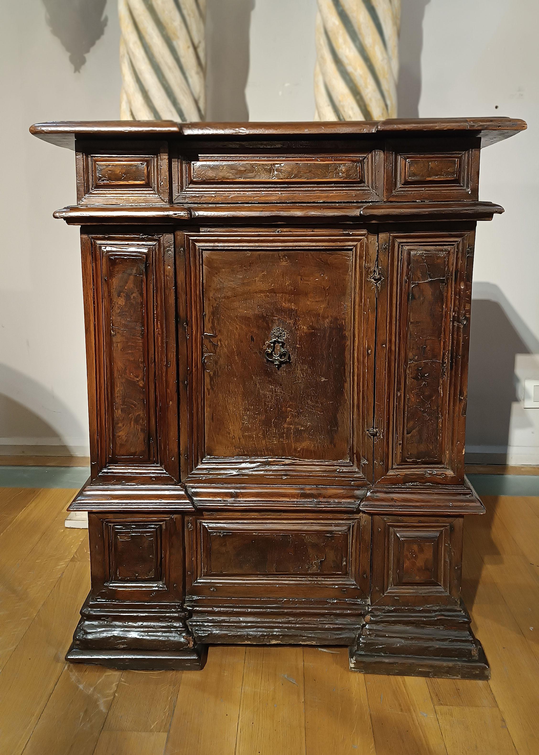 Beautiful and sophisticated candle holder small sideboard in solid walnut. The piece of furniture has a door with a small handle in lost wax cast bronze, while the folding top was used to store candles. The feet and decorations are characterized by