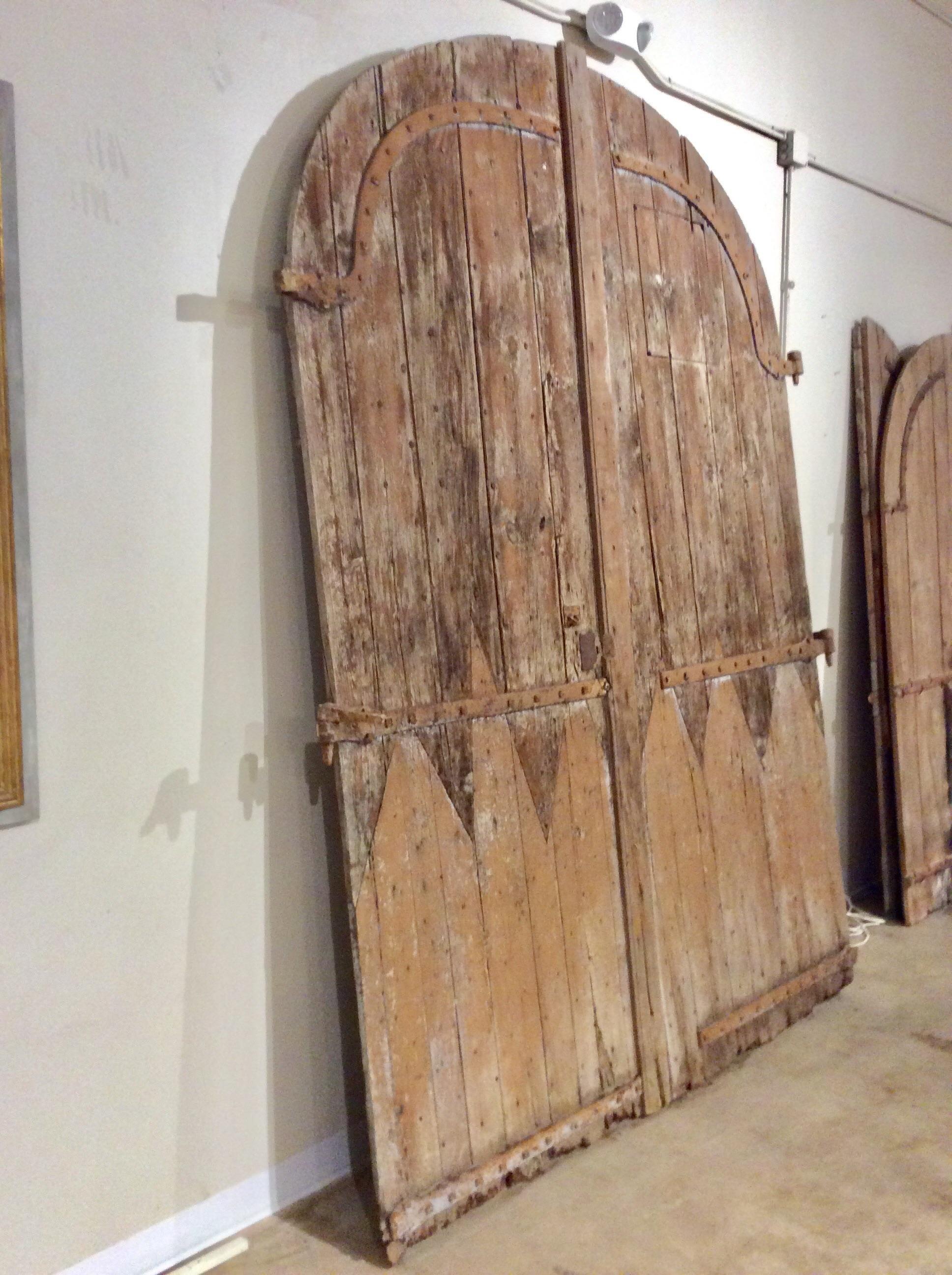 Found in the South of France, these monumental Early 1800s French Arched Wood Doors were salvaged from a 19th century French chateau. They would have been on the ground floor, attached to the building. Each door is made of mixed wood, pine and oak,