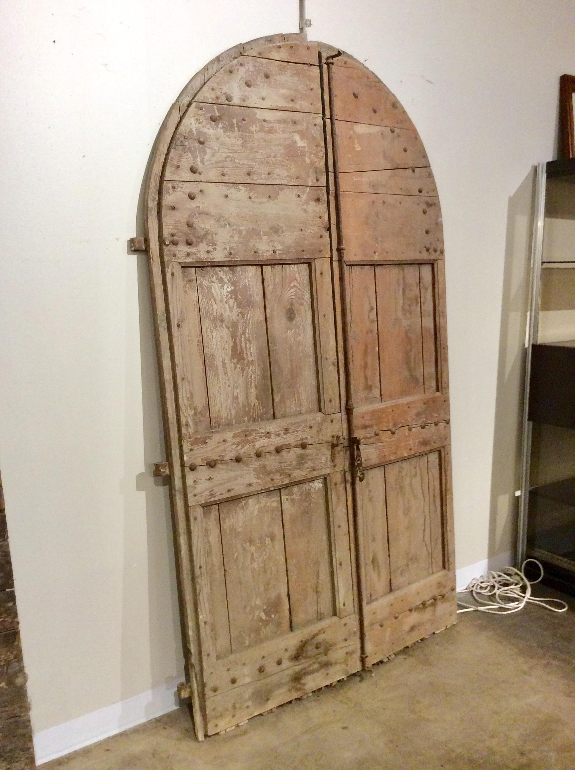 Found in the South of France, these monumental Early 1800s French Arched Wood Doors were salvaged from a 19th century French chateau. They would have been on the ground floor, attached to the building. Each door is made of pine and retain most of