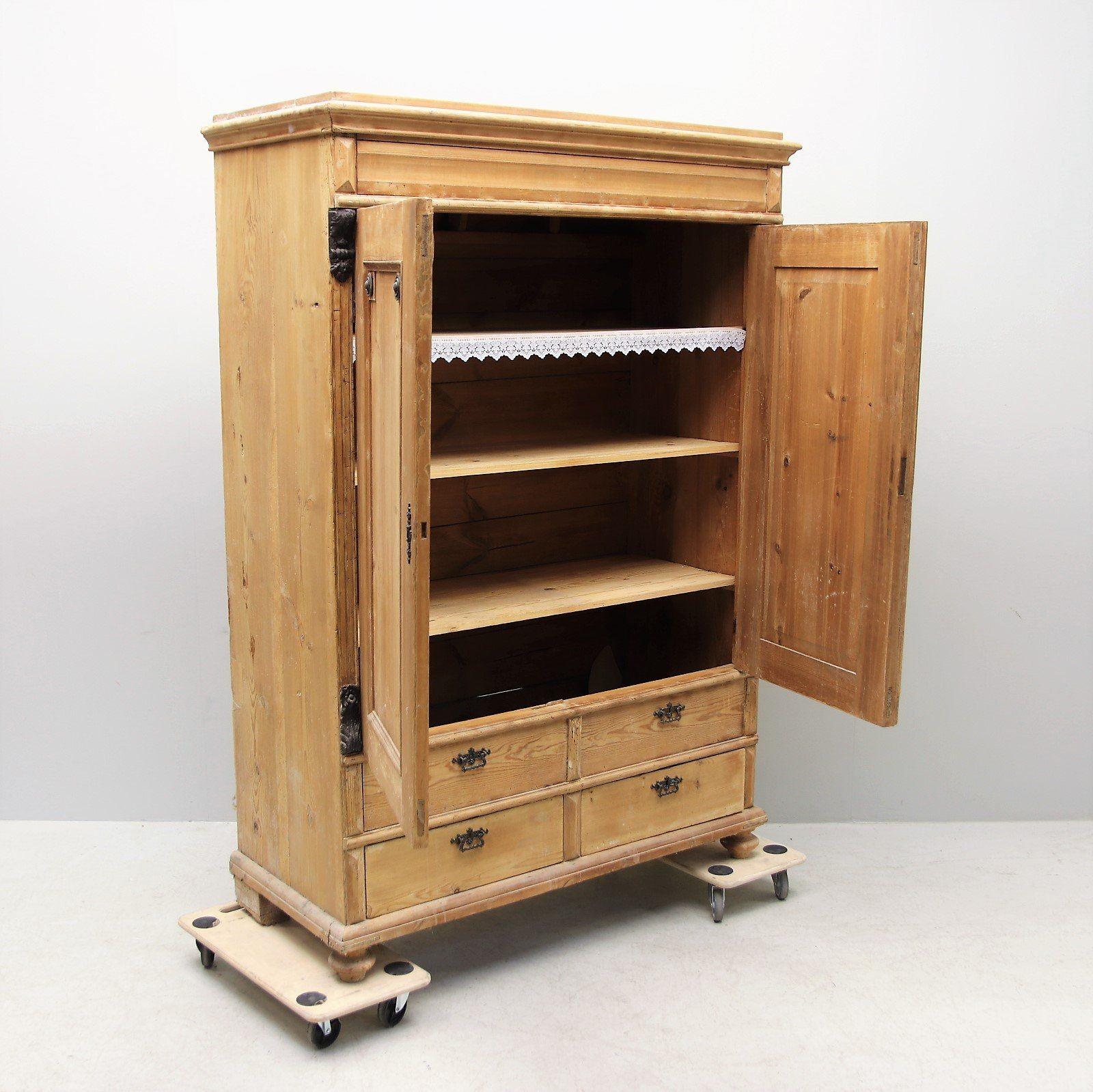 Early 1800s large Swedish pine armoire with original hardware. Classic and elegant design, timeless simple carved details, and bun feet, this large armoire features four lower drawers and two main cabinet doors that open to three interior shelves.