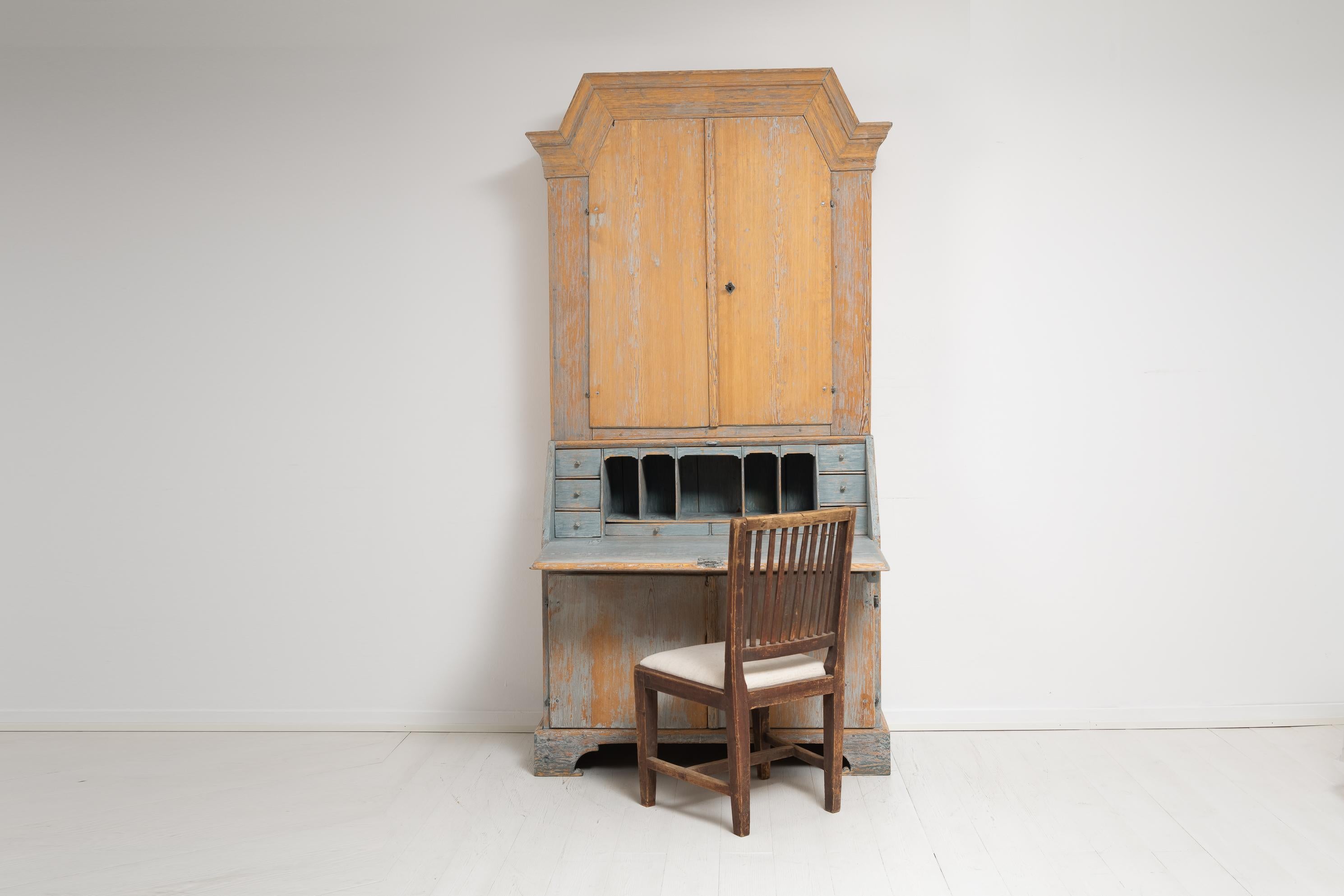 Northern Swedish pine secretary cabinet in two parts. The cabinet is a country house furniture from the early 19th century, between 1810 to 1820, and is made in the baroque style. The cabinet is tall and solid with clean elegant lines and simple