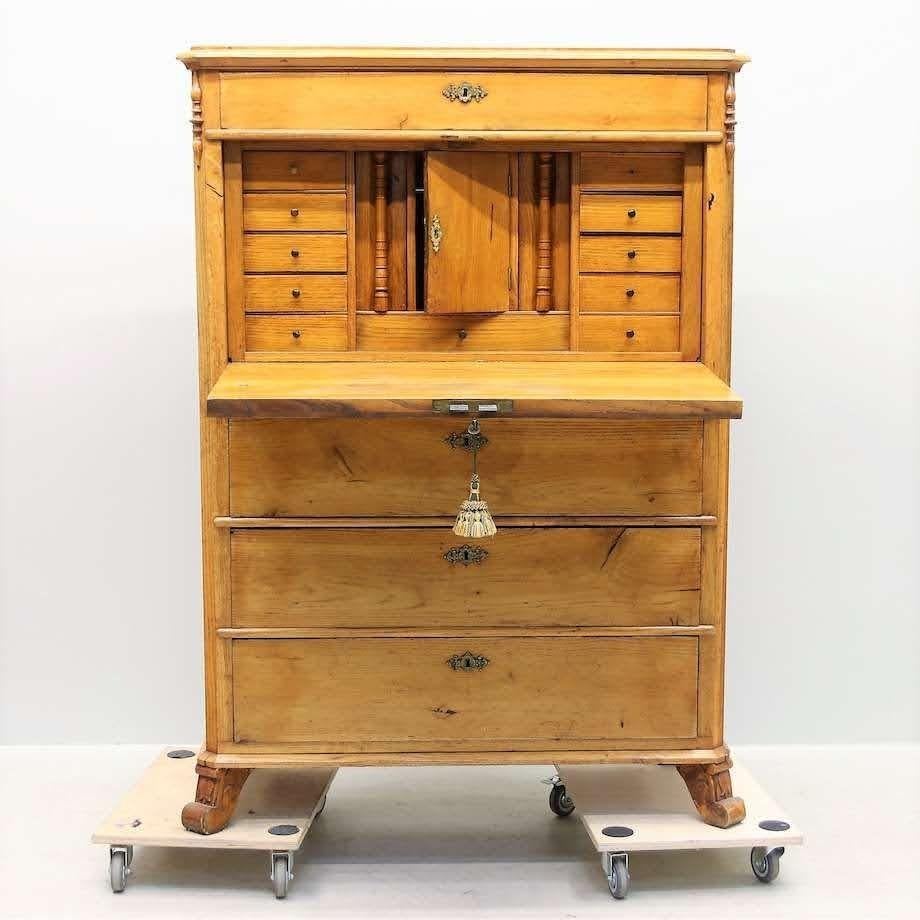 Early 1800s Swedish pine secretary with original brass hardware. Substantial and gorgeous, the authentic aged Swedish pine glows with a golden patina. With a chest of three roomy drawers on the bottom, the hinged secretary desktop opens to reveal 11
