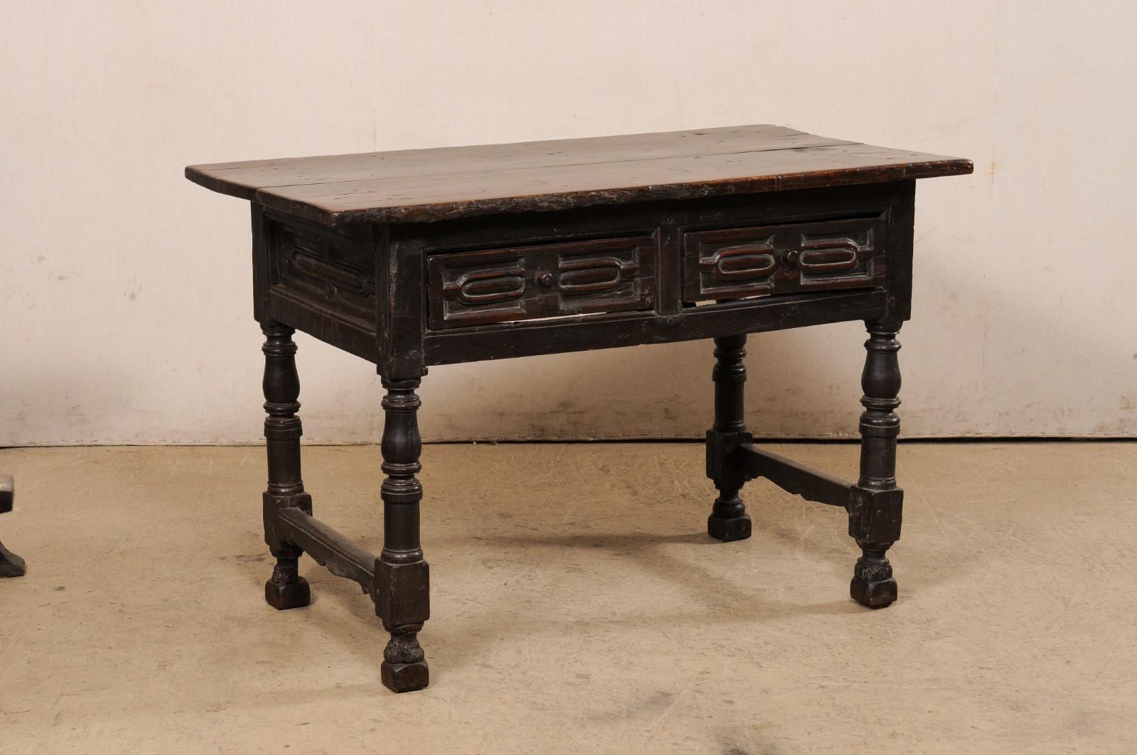 An Italian carved walnut wood occasional table with drawers, from the early 18th century (possibly 17th century). This antique table from Italy, created from rich walnut wood, has a rectangular-shaped top, which overhangs the carved apron below