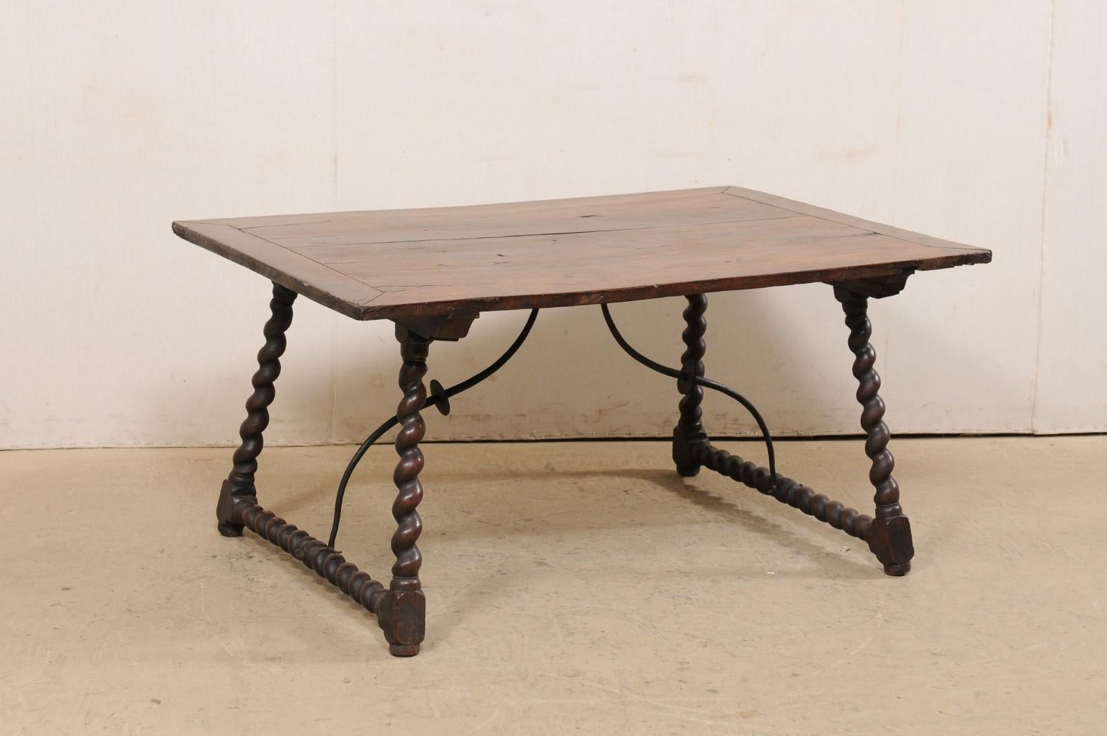 An Italian wooden barley twist leg table, with decorative forged-iron stretcher, from the early 18th century. This antique occasional table from Italy features a rectangular-shaped top, which is raised upon a pair of nicely-carved barley twist,