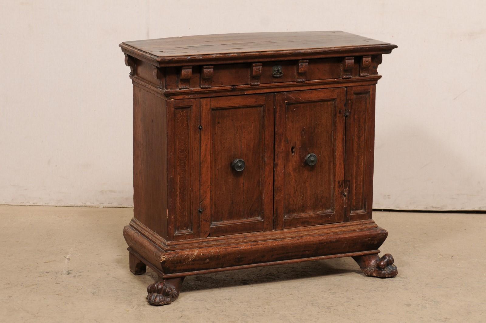 An Italian walnut two-door cabinet from the early 18th century. This antique cabinet from Italy features a rectangular-shaped top, with handsome bracket-style carvings adorning it's underside, atop a case which houses a top drawer (which is hidden