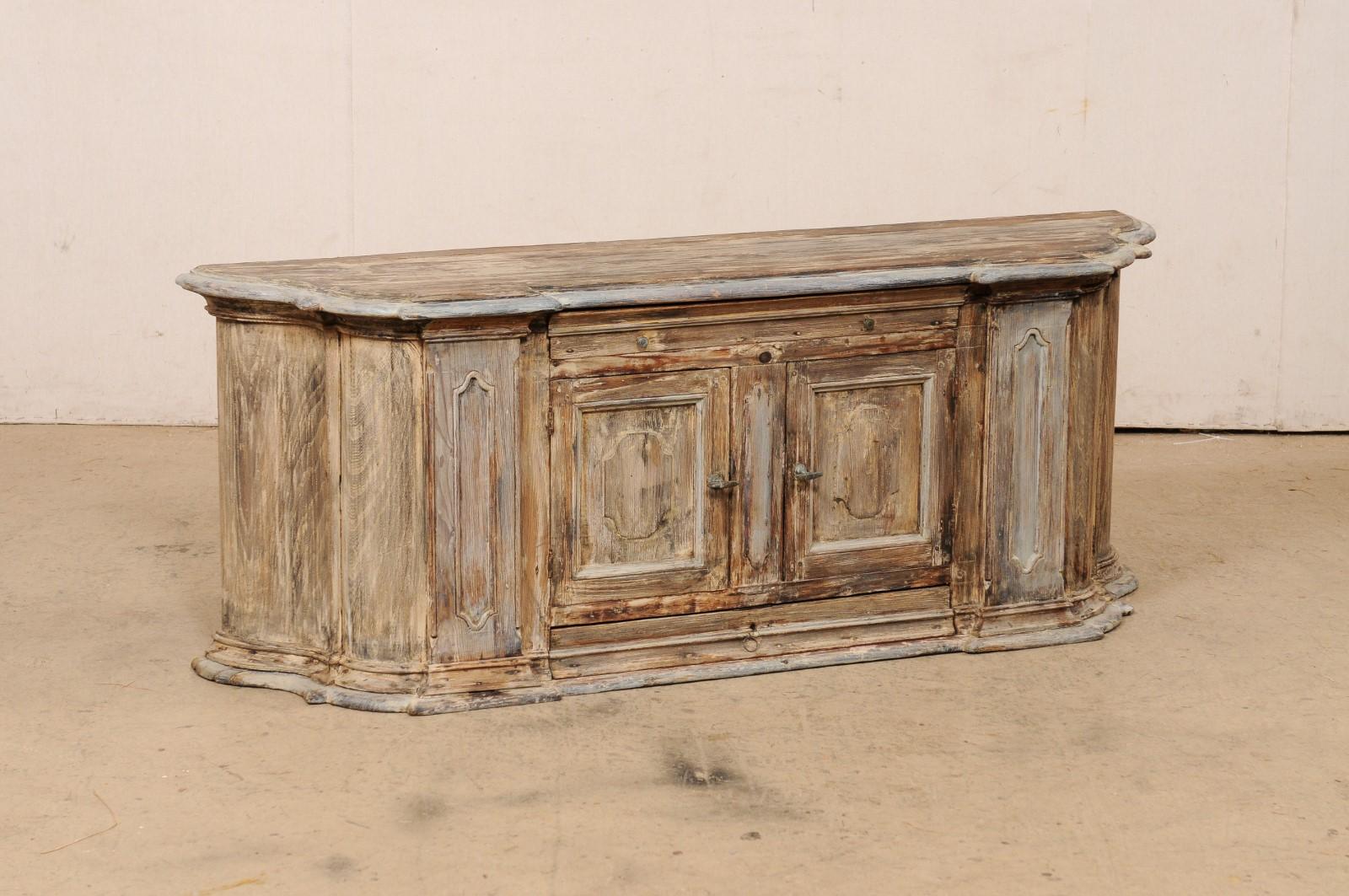 An Italian carved-wood bench with storage from the early 18th century. This antique bench from Italy has a flattened backside, with a curved/bowed (half-oval shape) front design with a double break-front step out flanking its center before rounding
